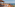 Ocean view rooftop terrace with sunbeds, lounge chairs, and thatched roof.