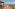 Ocean view rooftop terrace with sunbeds, lounge chairs, and thatched roof.