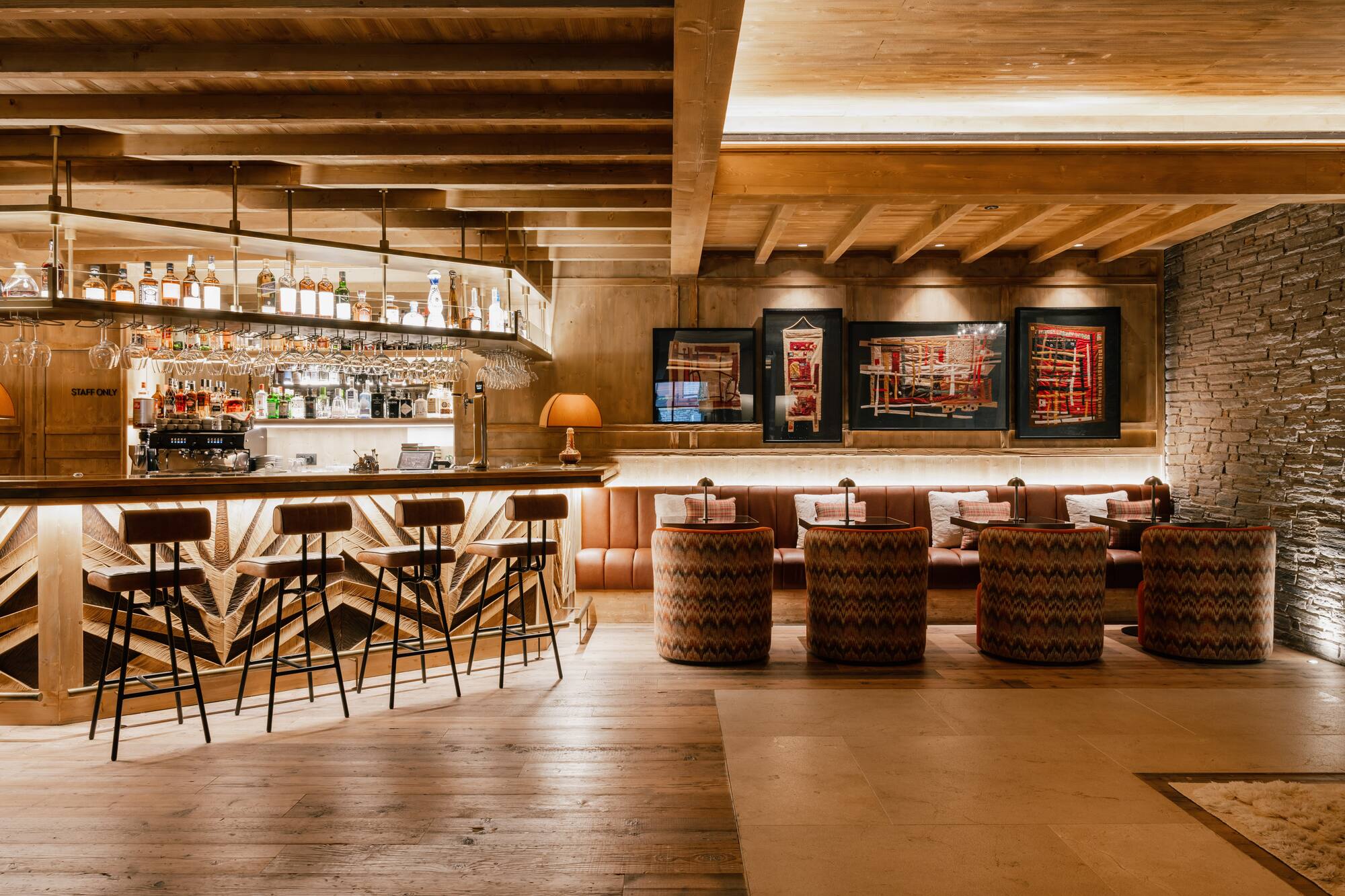 Bar de hotel estilo chalet con barra de madera y asientos lounge.
