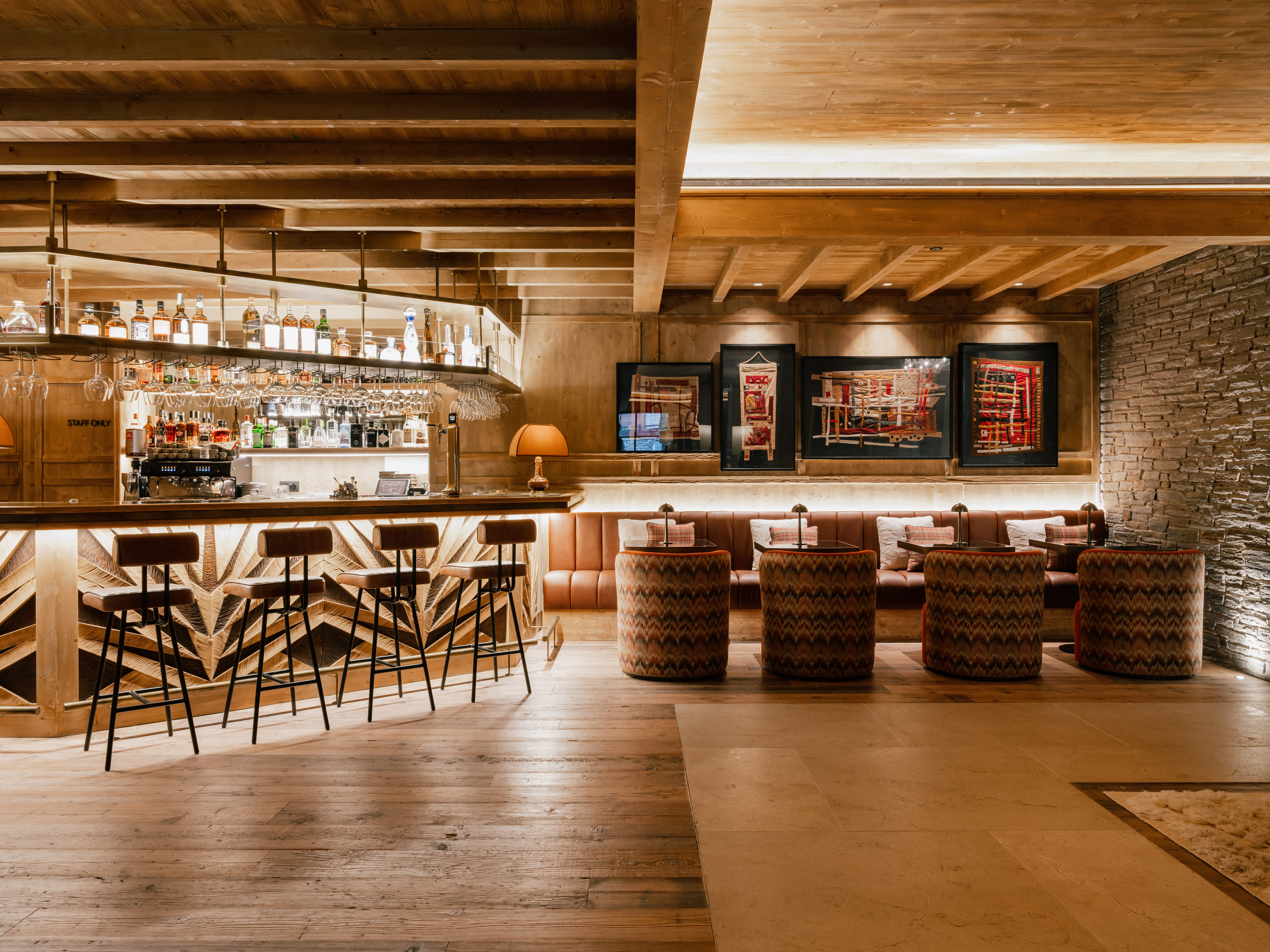 Bar de hotel estilo chalet con barra de madera y asientos lounge.