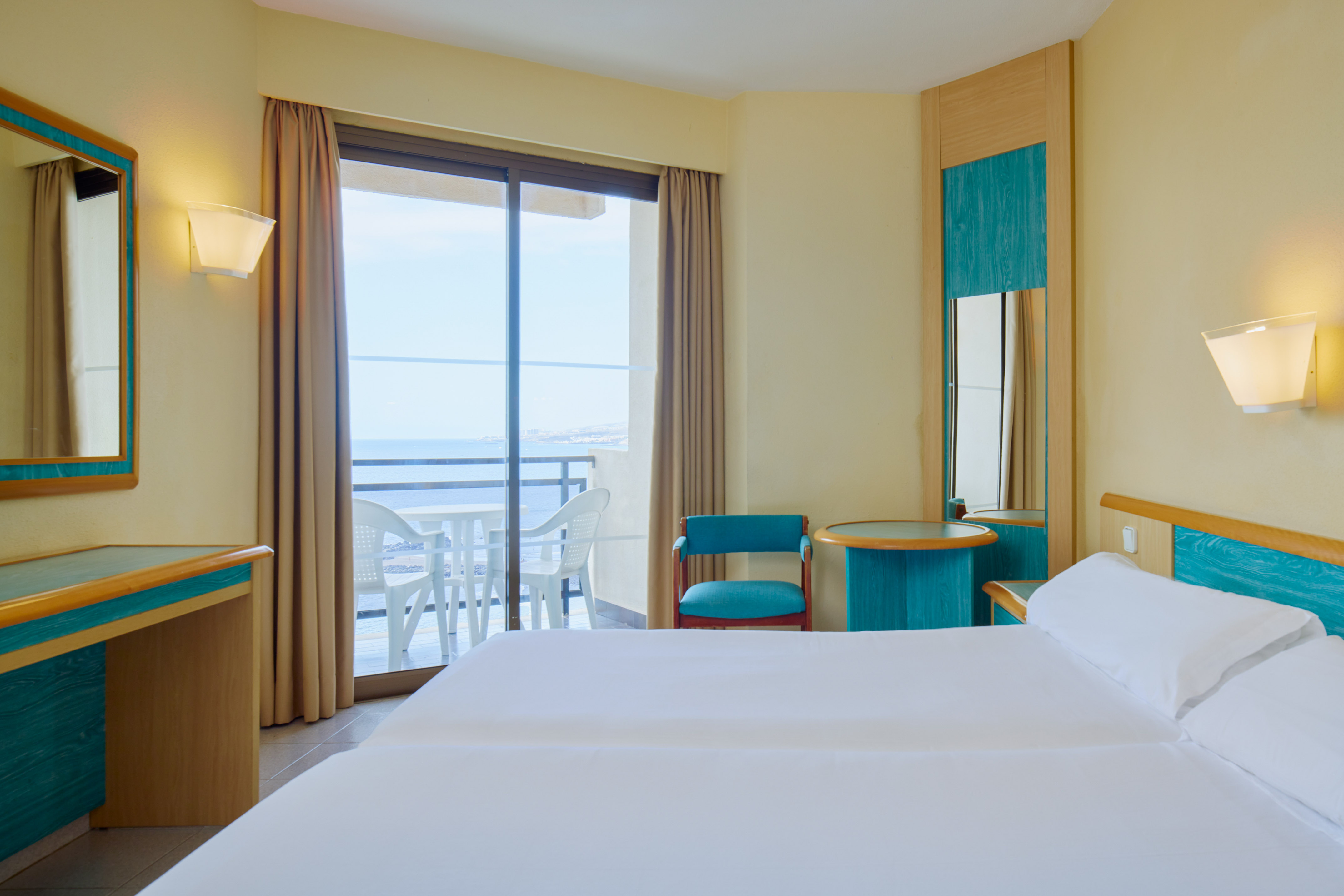 Hotel room with private balcony, ocean view, double bed, and desk.