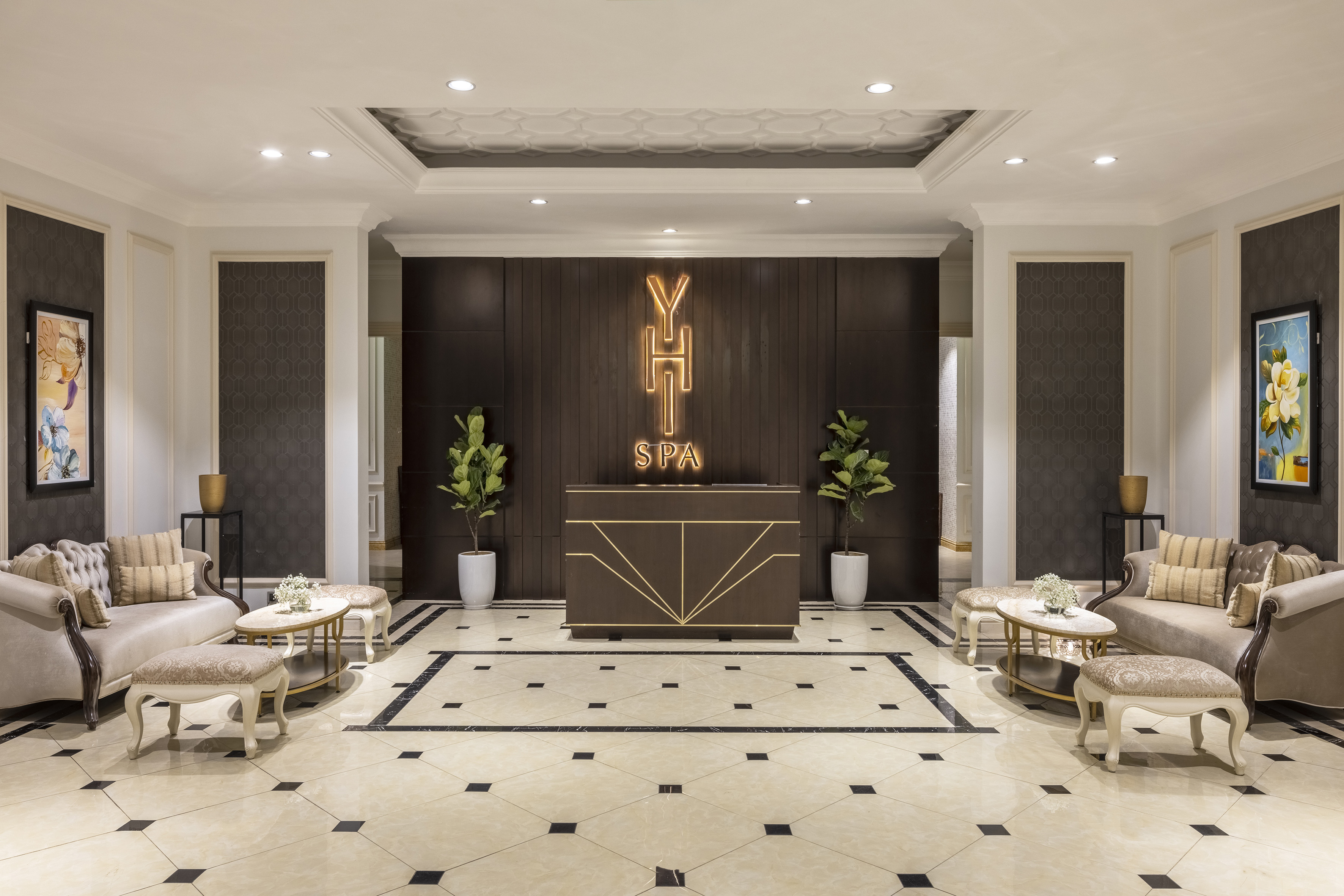 Elegant spa lobby reception with YHT SPA neon sign, plush seating, and tiled floor.