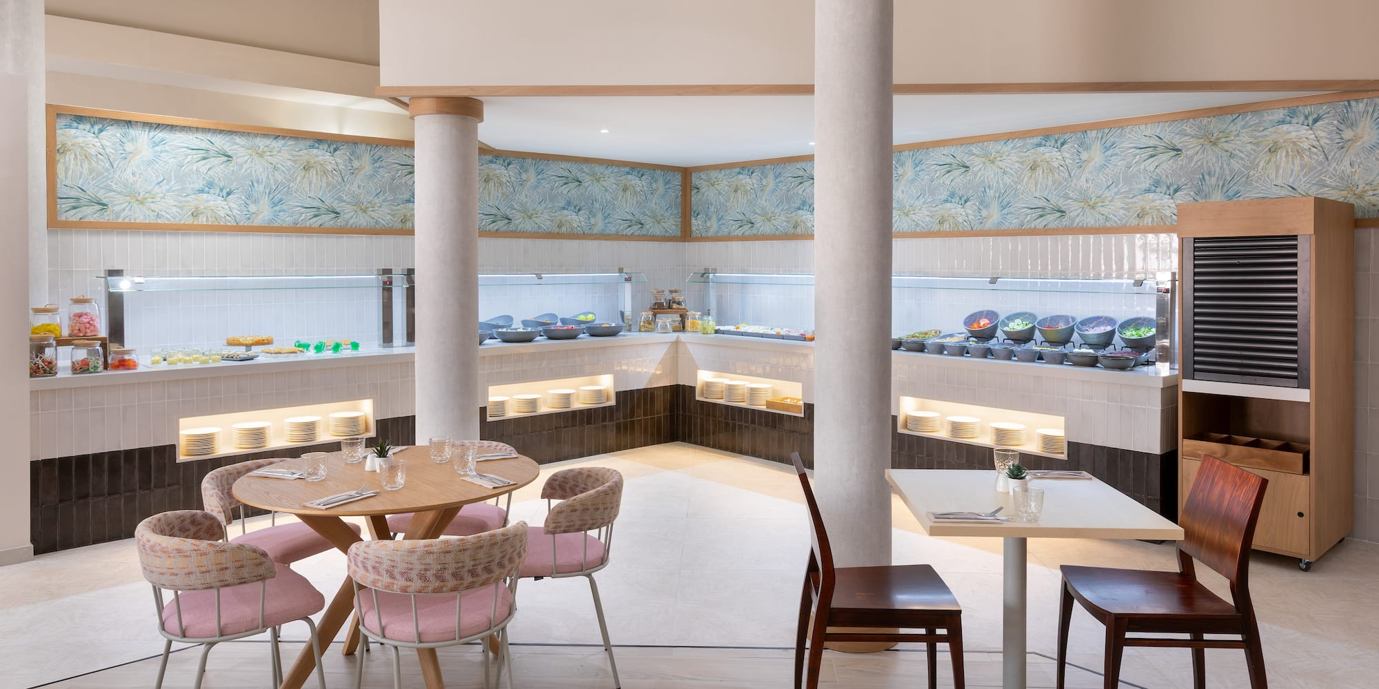 Bright buffet restaurant with fresh food displays, tropical wallpaper, and inviting seating.
