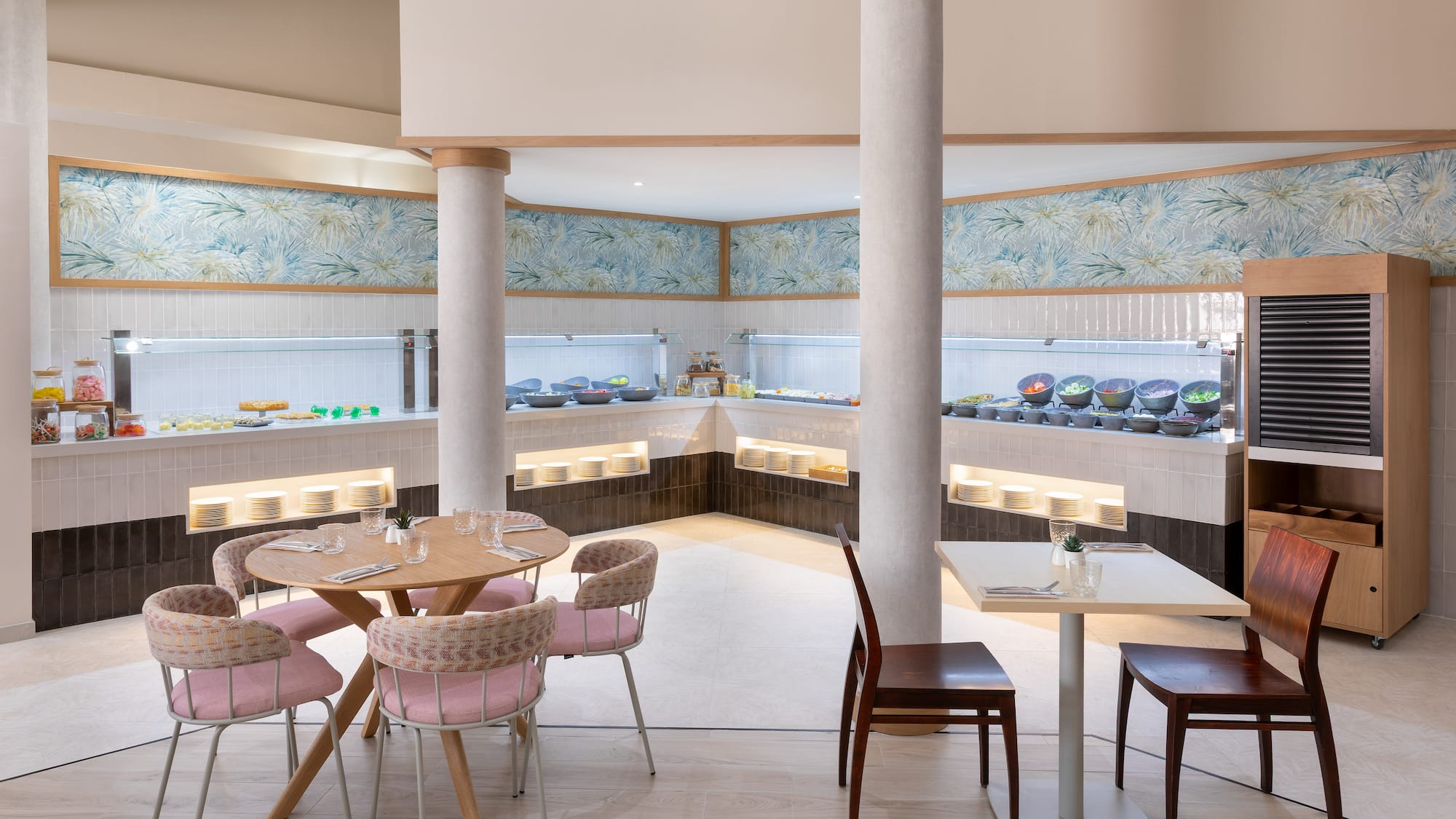 Bright buffet restaurant with fresh food displays, tropical wallpaper, and inviting seating.
