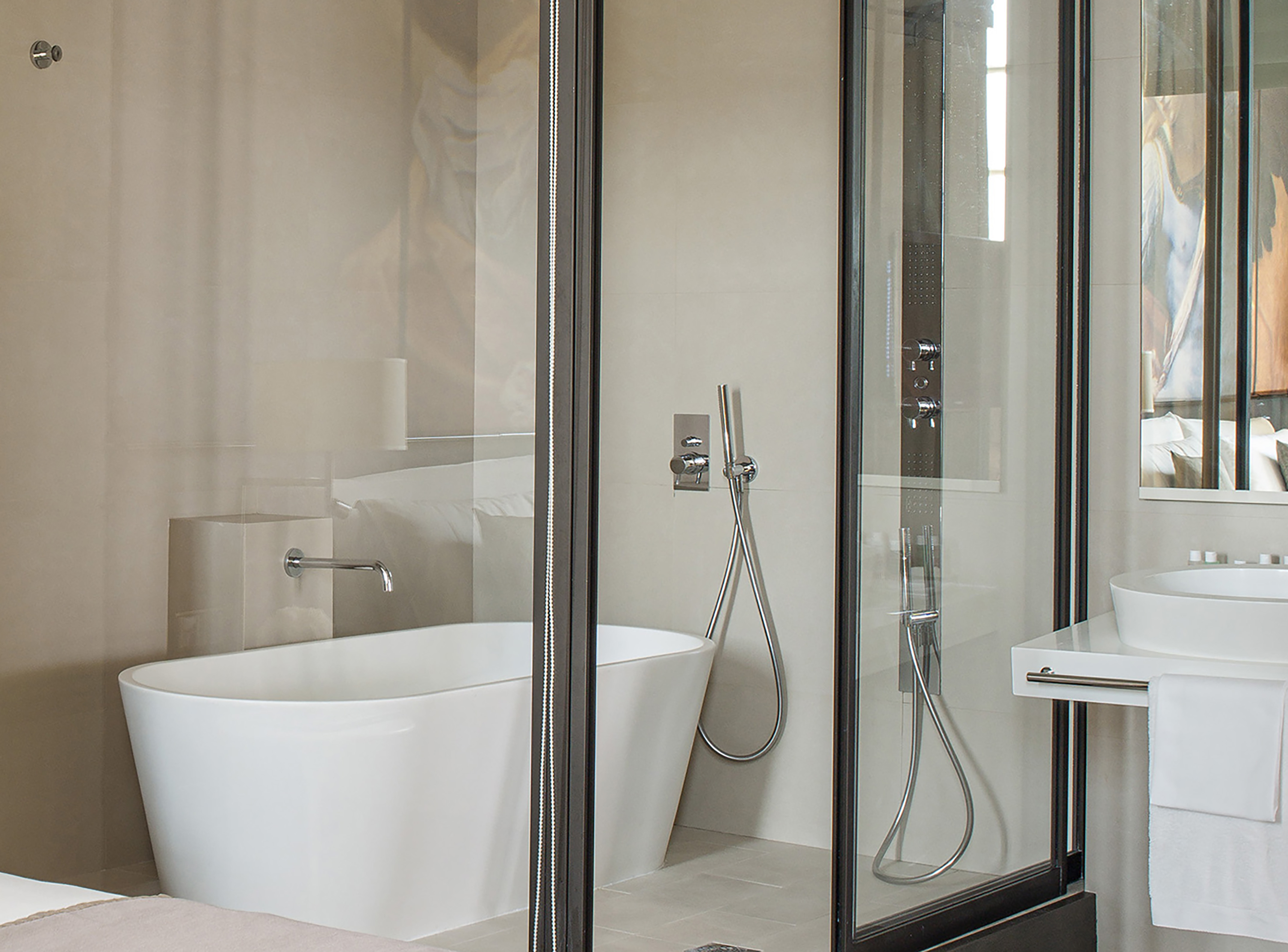 Modern hotel bathroom with freestanding tub and glass shower.