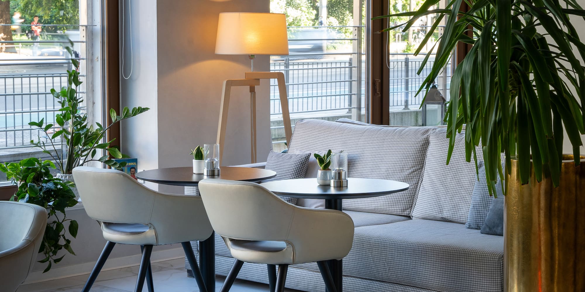 a room with a couch and tables and a lamp