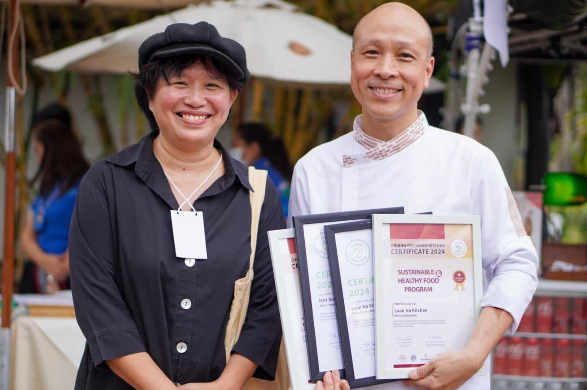 Smiling chef and woman with Chiang Mai Green Kitchen healthy food awards.