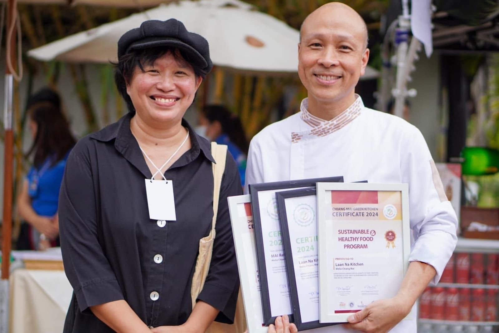 Smiling chef and woman with Chiang Mai Green Kitchen healthy food awards.