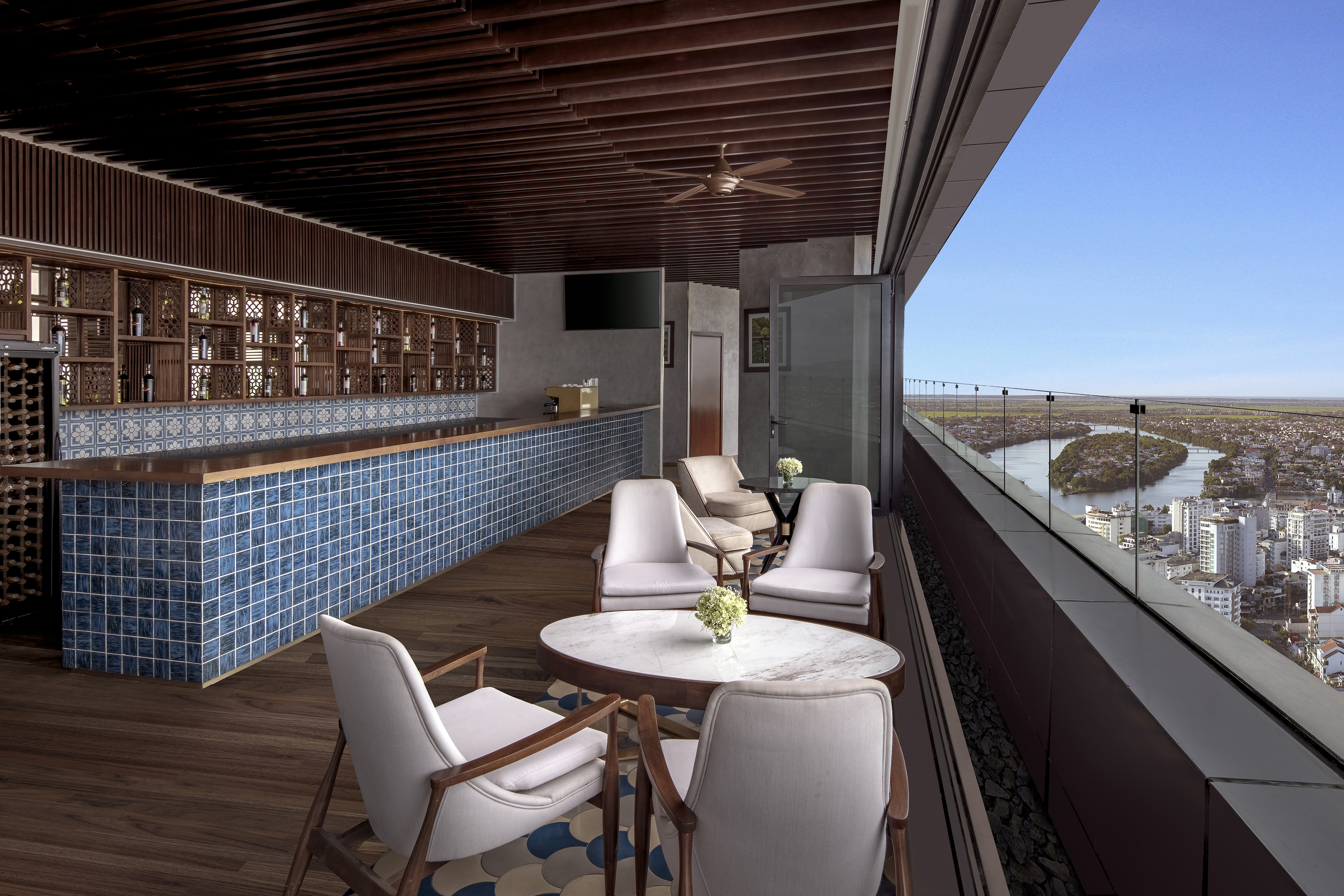 Rooftop bar with blue tiles, lounge seating, and panoramic city river view. - Meliá Vinpearl Hue, Hue City