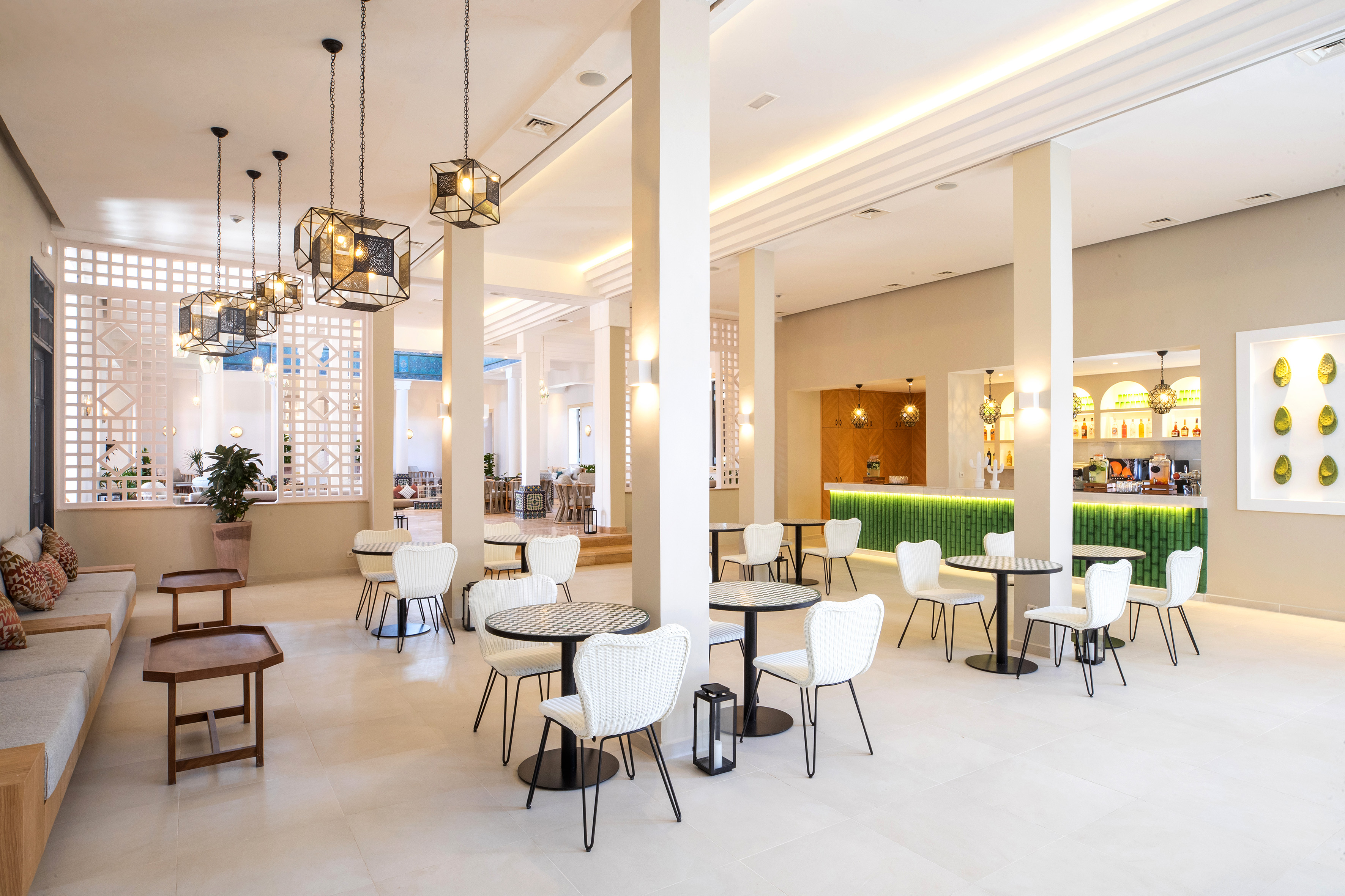 Stylish hotel lounge with modern seating, geometric lights, and a green bar.