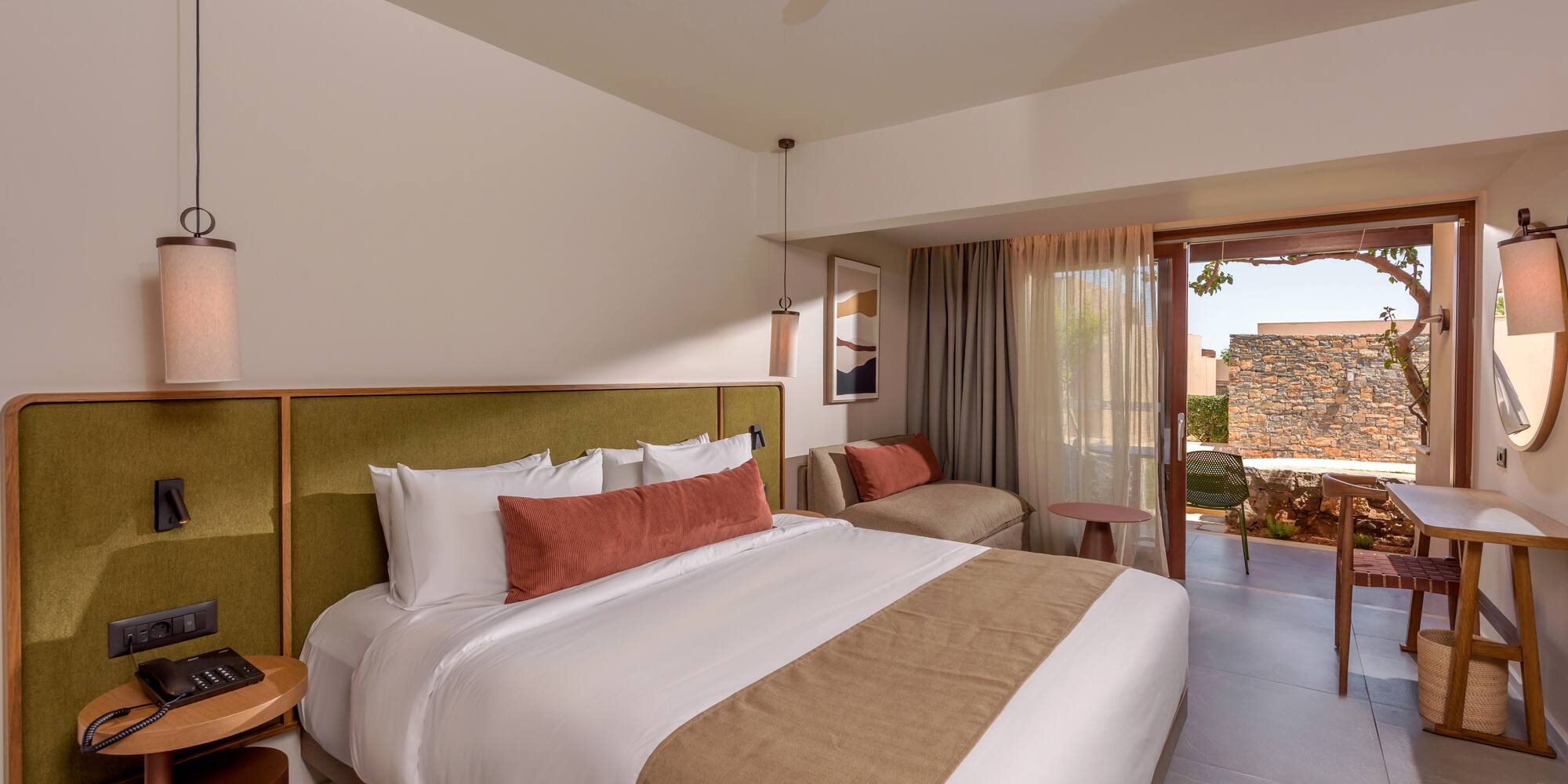 Luxury hotel bedroom with king bed, green headboard, and outdoor patio.