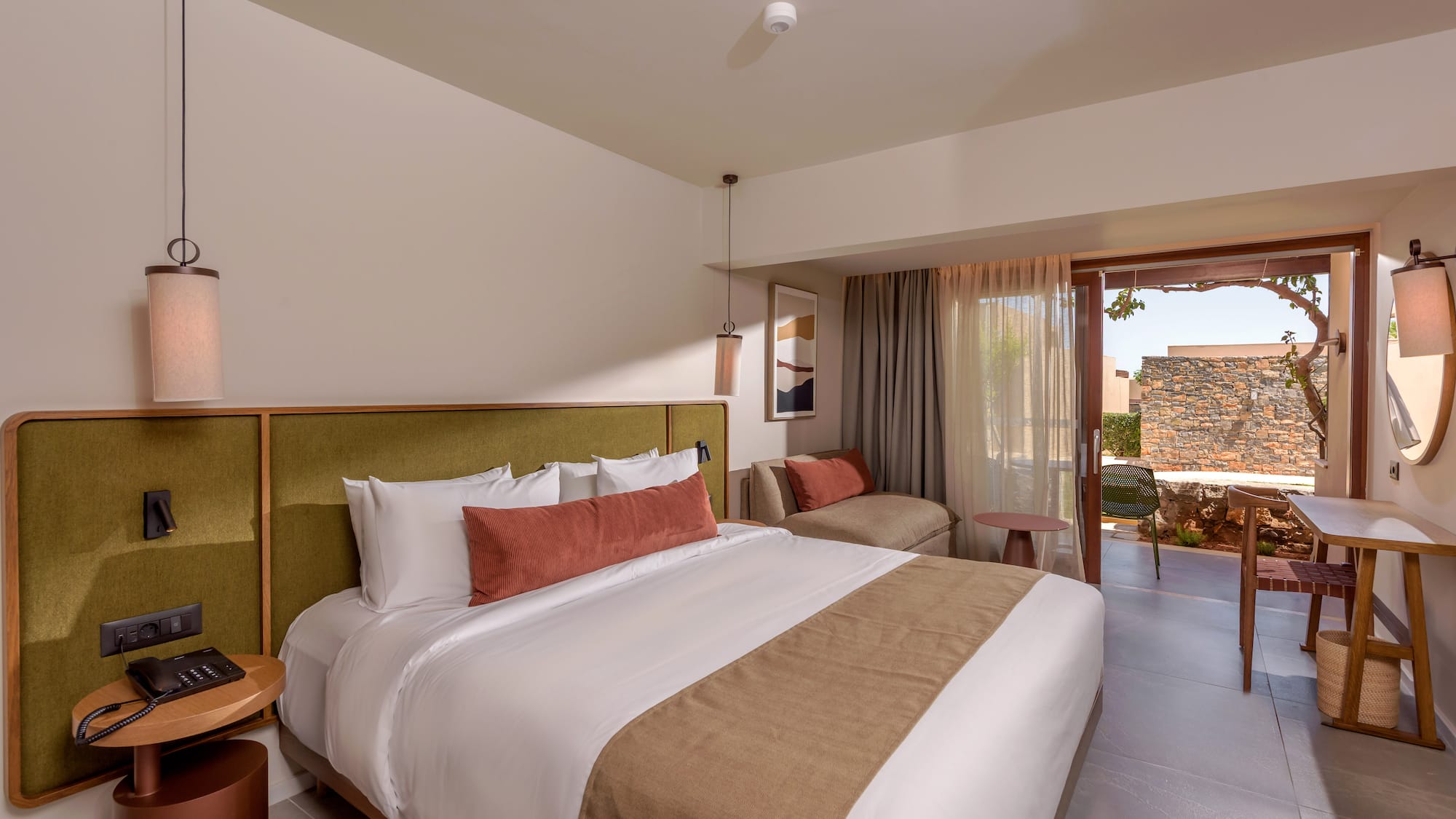 Luxury hotel bedroom with king bed, green headboard, and outdoor patio.