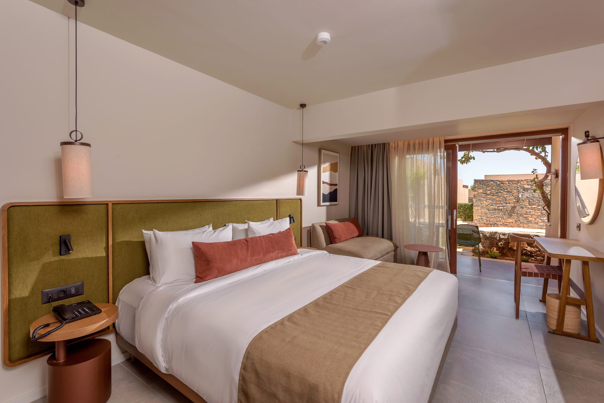 Luxury hotel bedroom with king bed, green headboard, and outdoor patio.