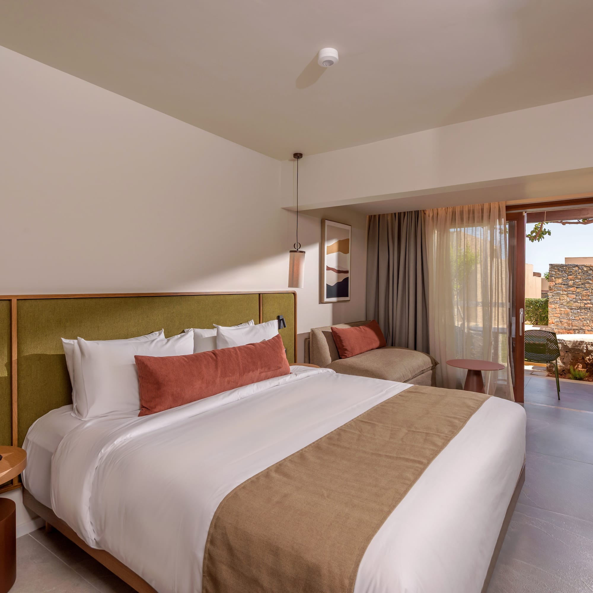Luxury hotel bedroom with king bed, green headboard, and outdoor patio.