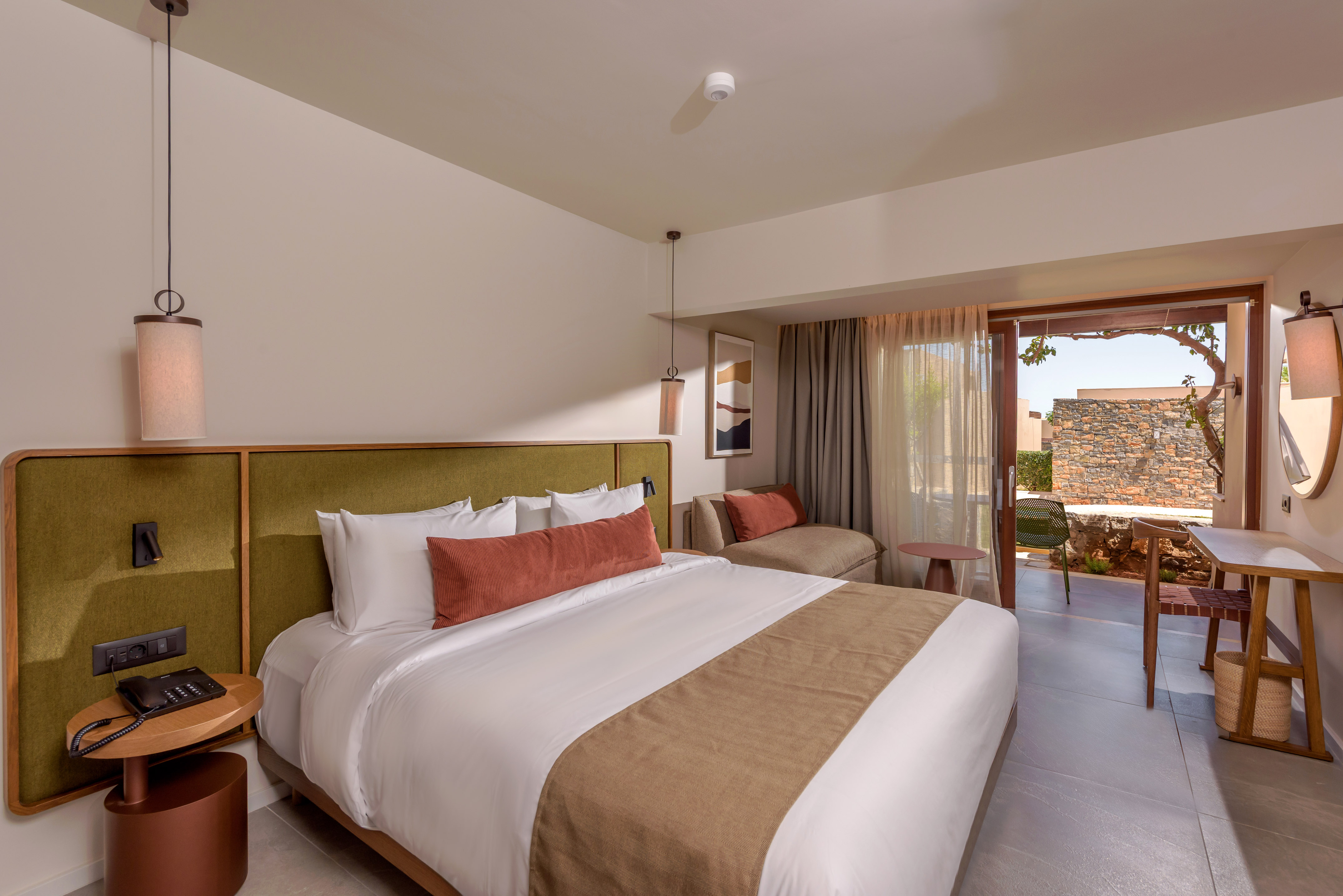 Luxury hotel bedroom with king bed, green headboard, and outdoor patio.