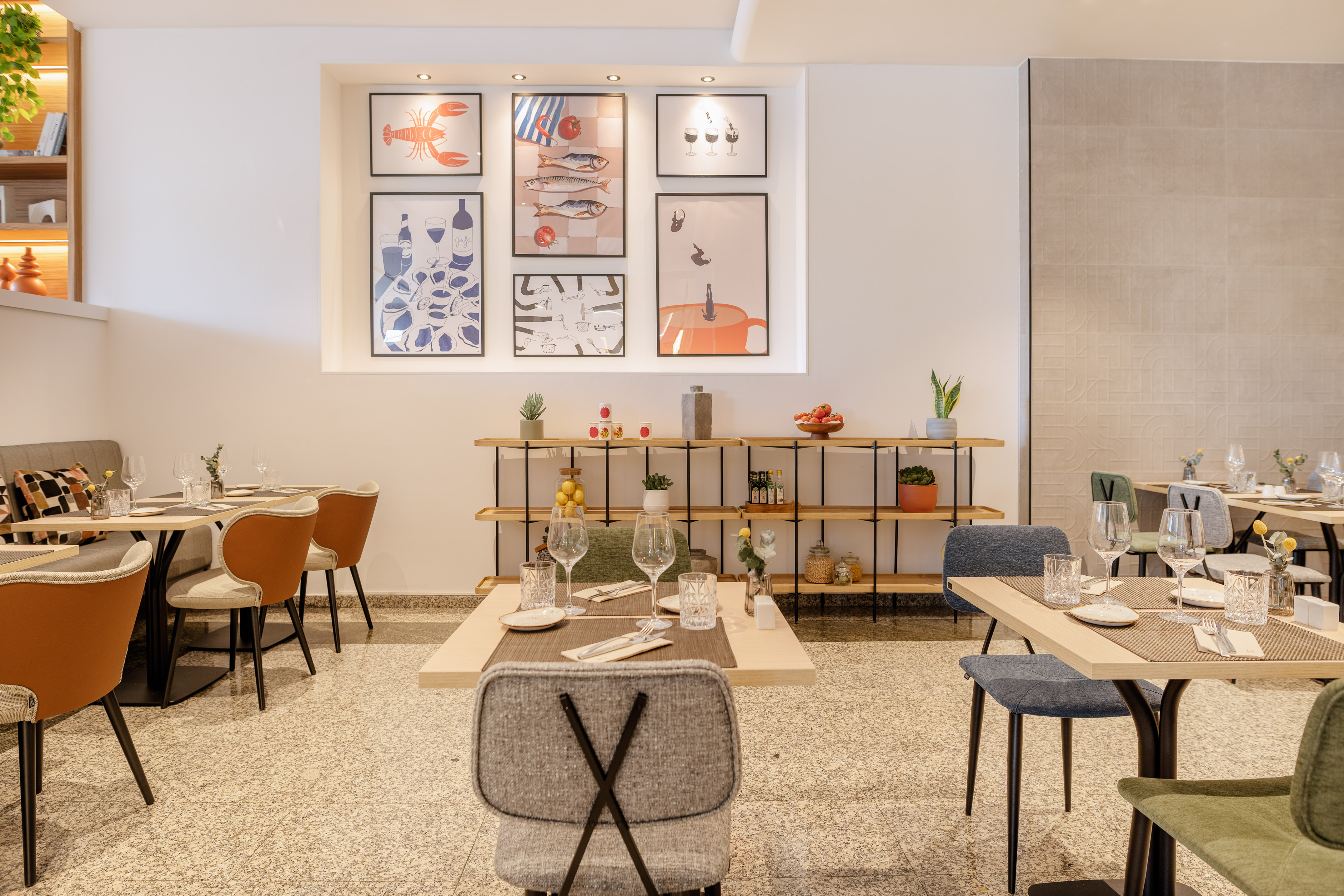 Modern restaurant dining room with set tables, food art, and decorative shelves.