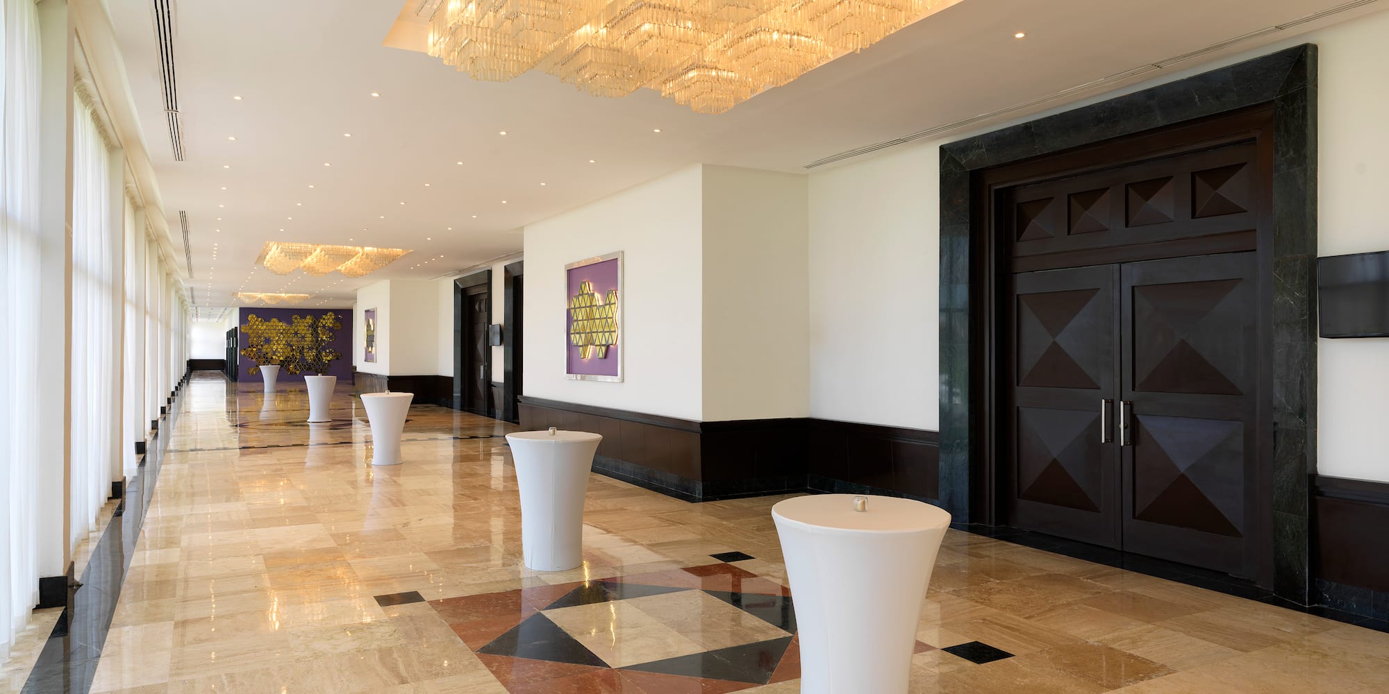 a hallway with marble floor and white tables