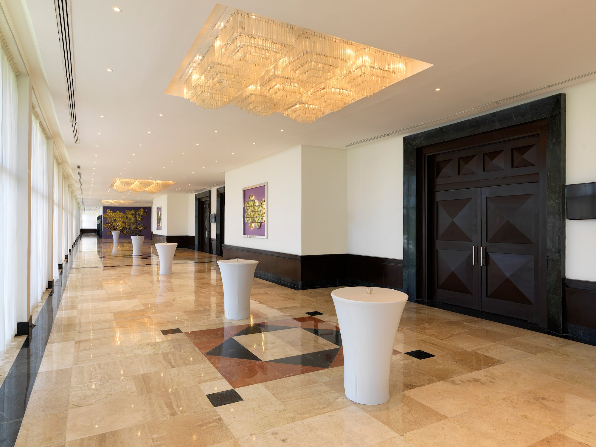 a hallway with marble floor and white tables