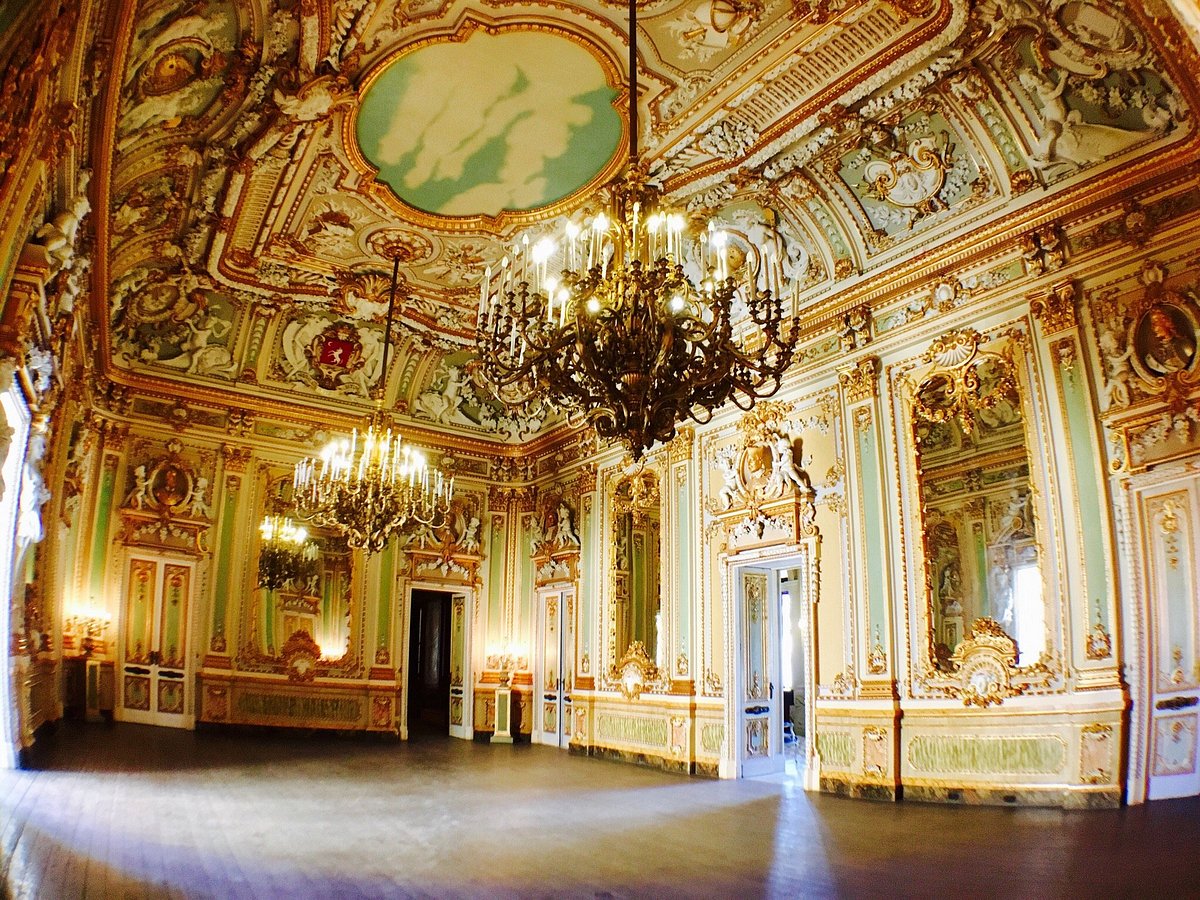 Ornate grand ballroom with golden decor, chandeliers, and fresco ceiling.
