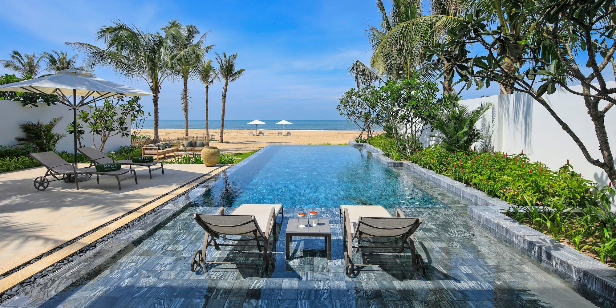 a pool with chairs and a beach in the background