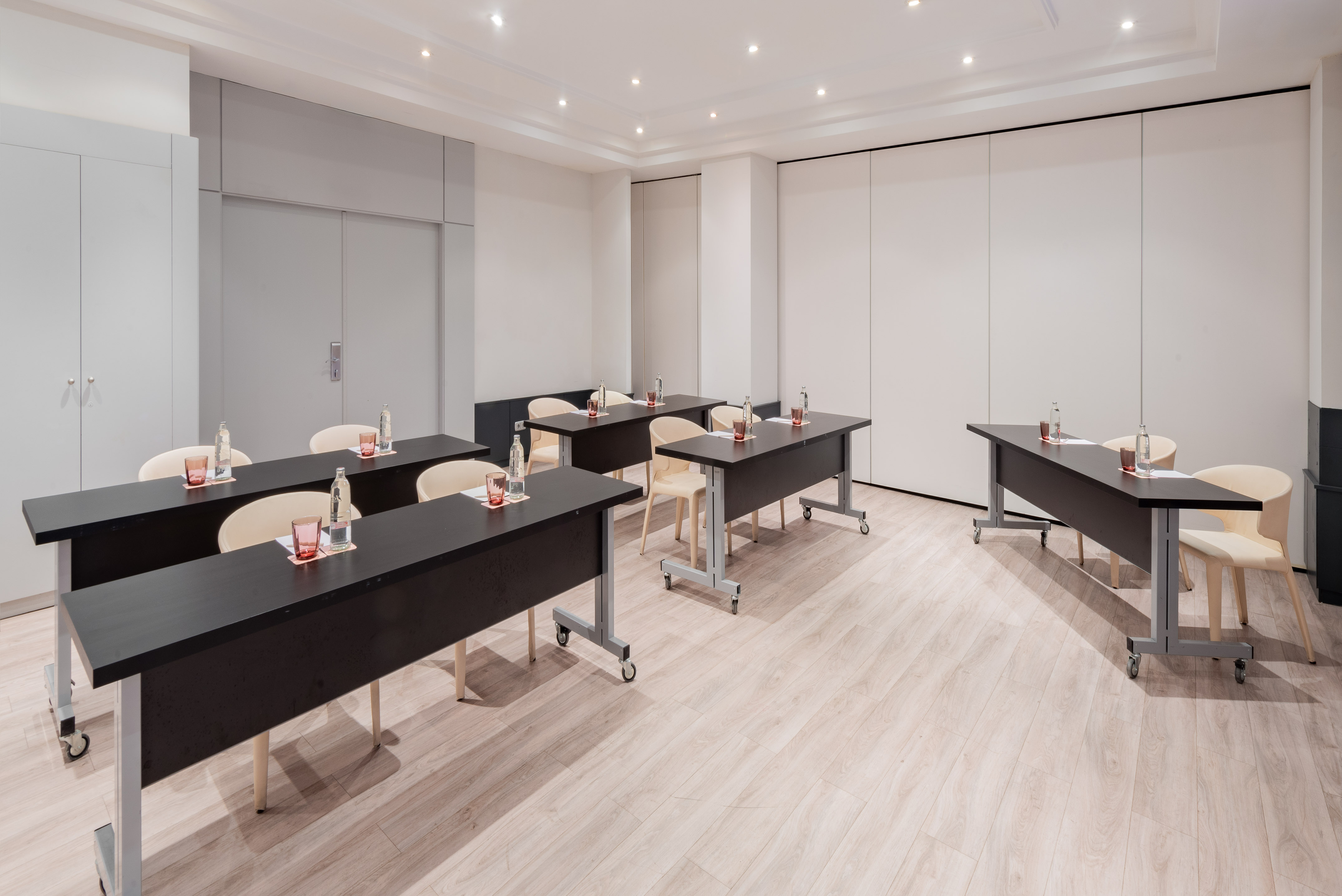 Modern meeting room with dark tables, light chairs, and light wood floor.