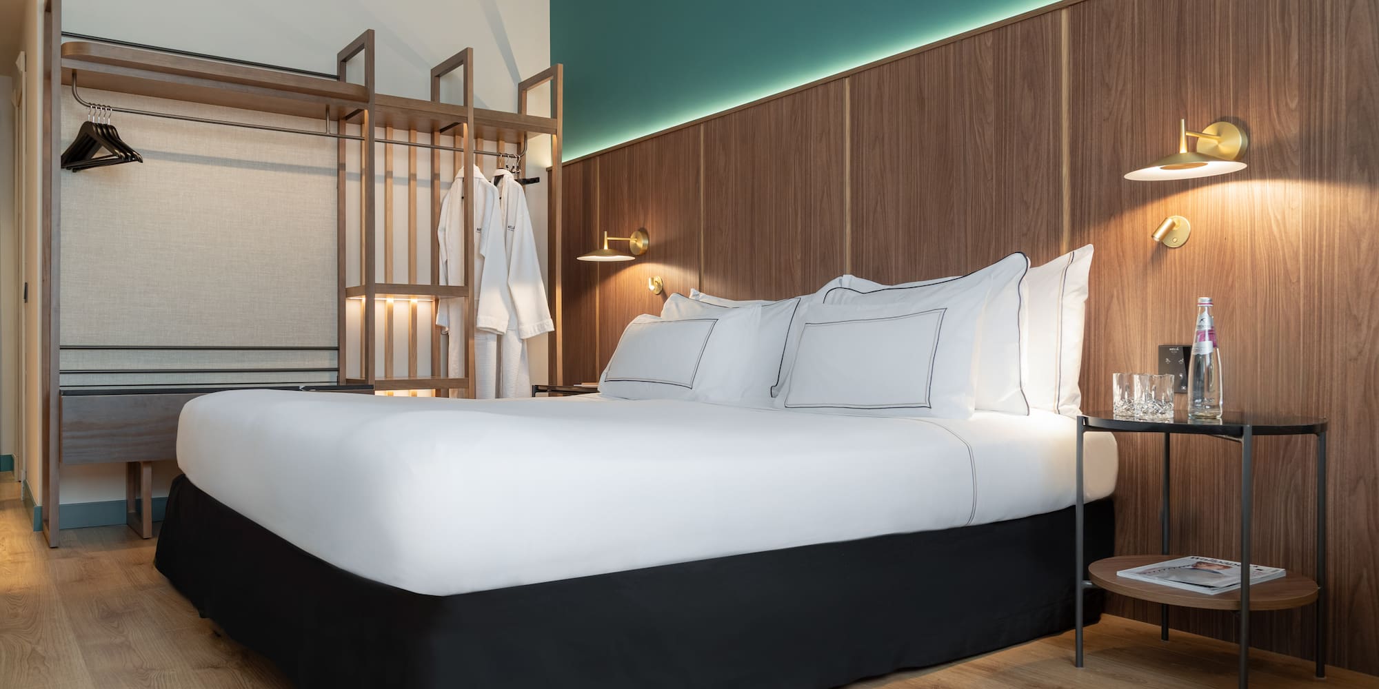 a bed with white sheets and a wood wall