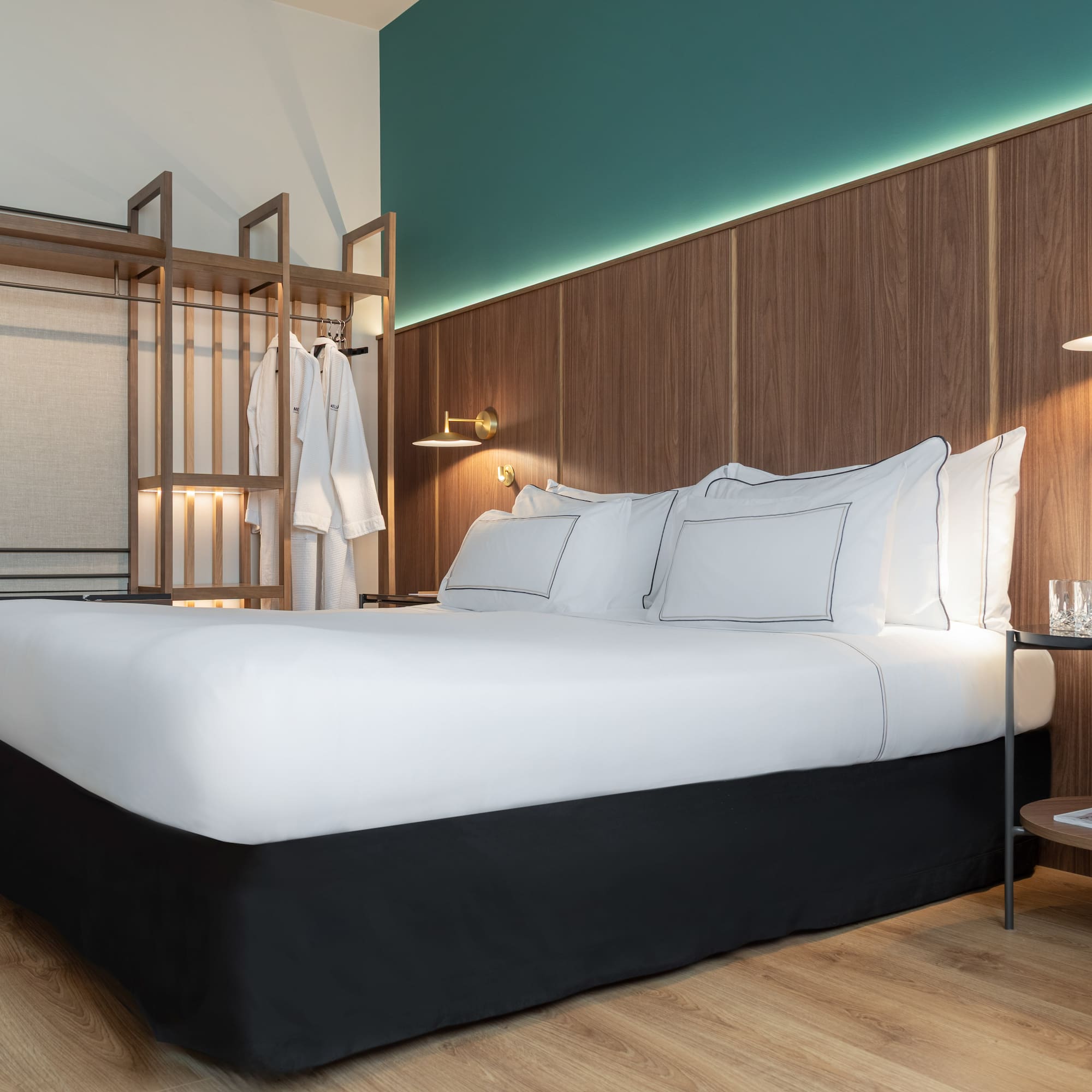 a bed with white sheets and a wood wall