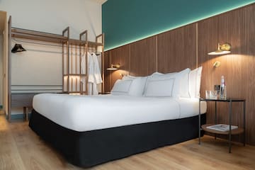 a bed with white sheets and a wood wall