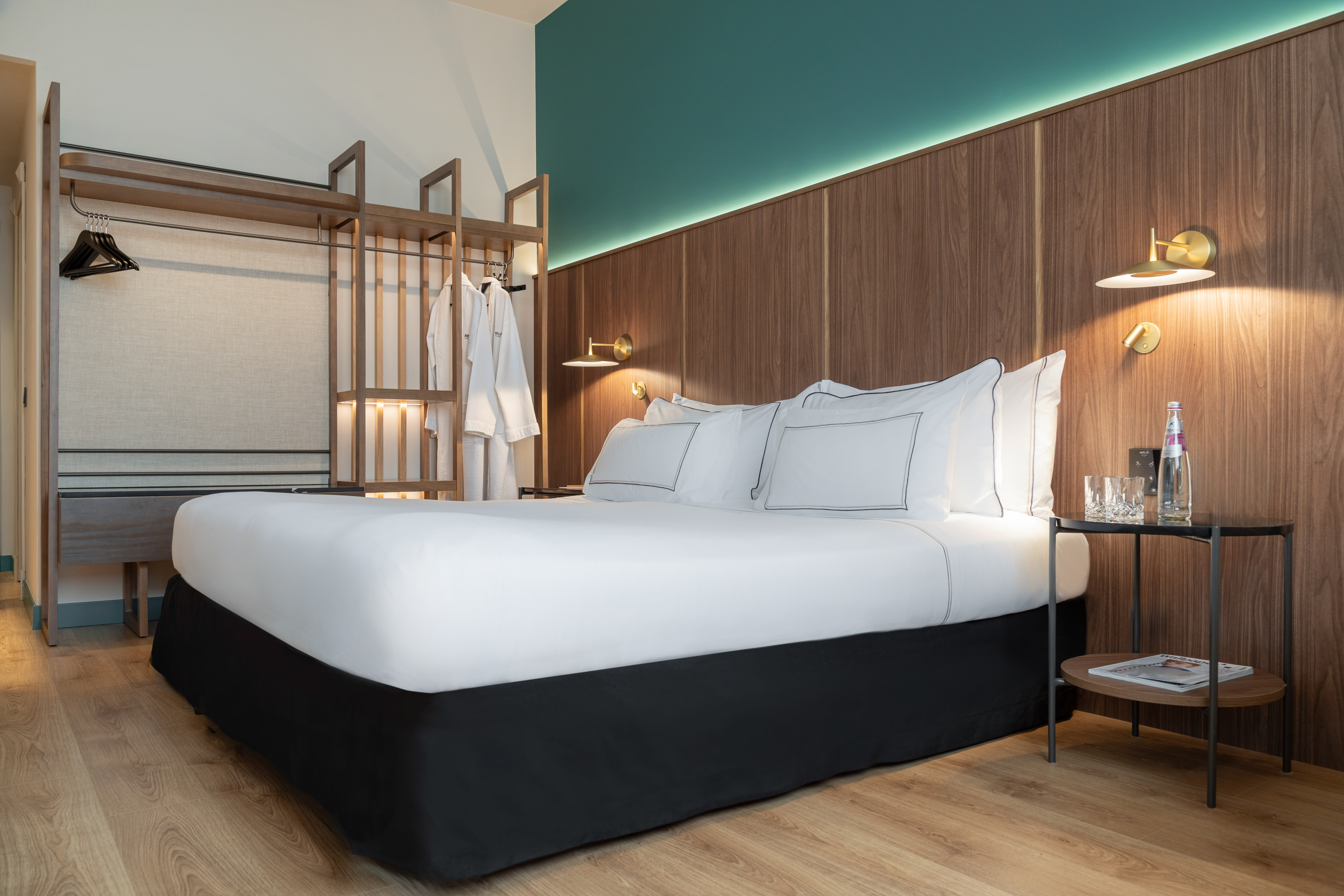 Modern hotel bedroom with white bed, wooden headboard, and built-in wardrobe.