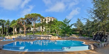 a pool with lounge chairs and trees in the background