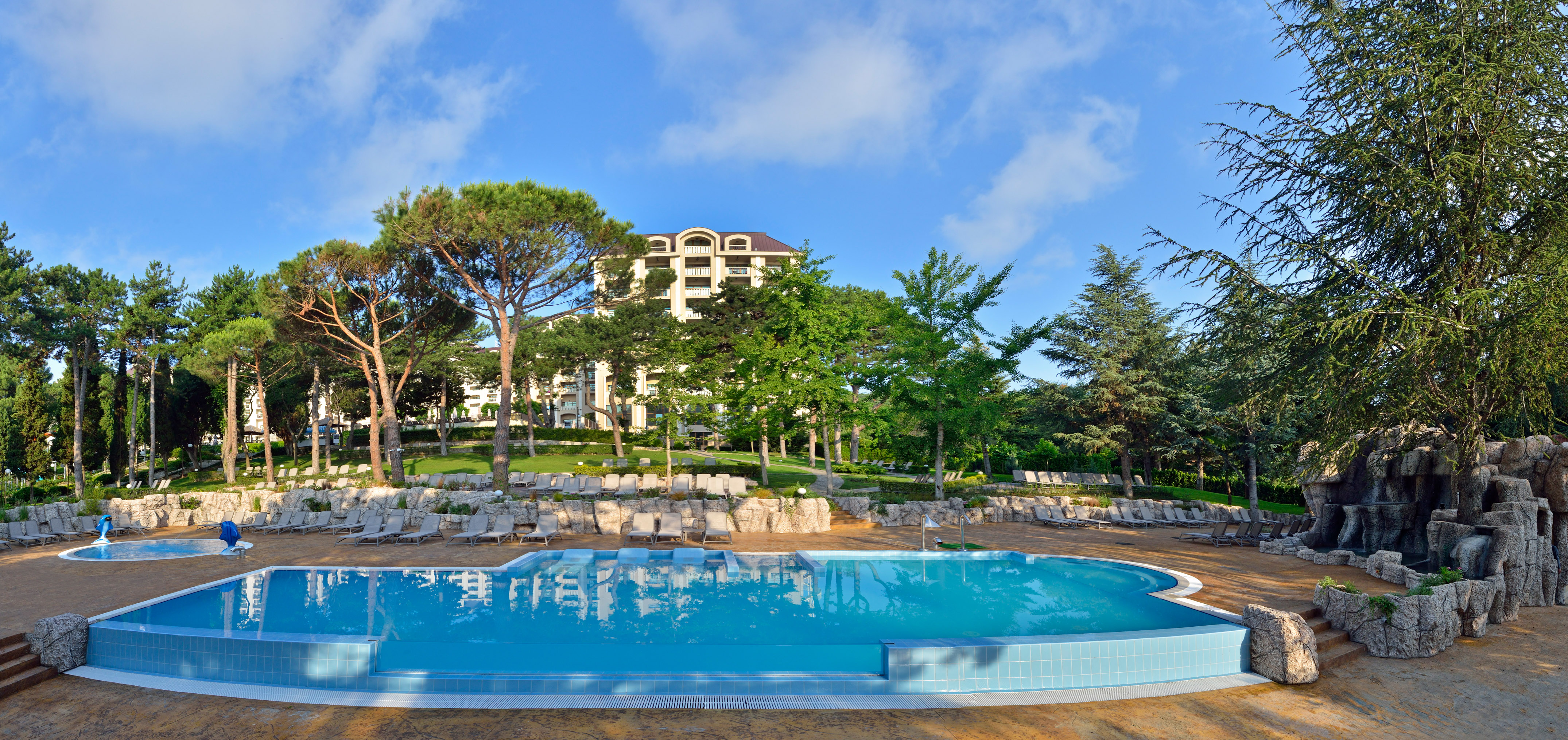 a pool with lounge chairs and trees in the background