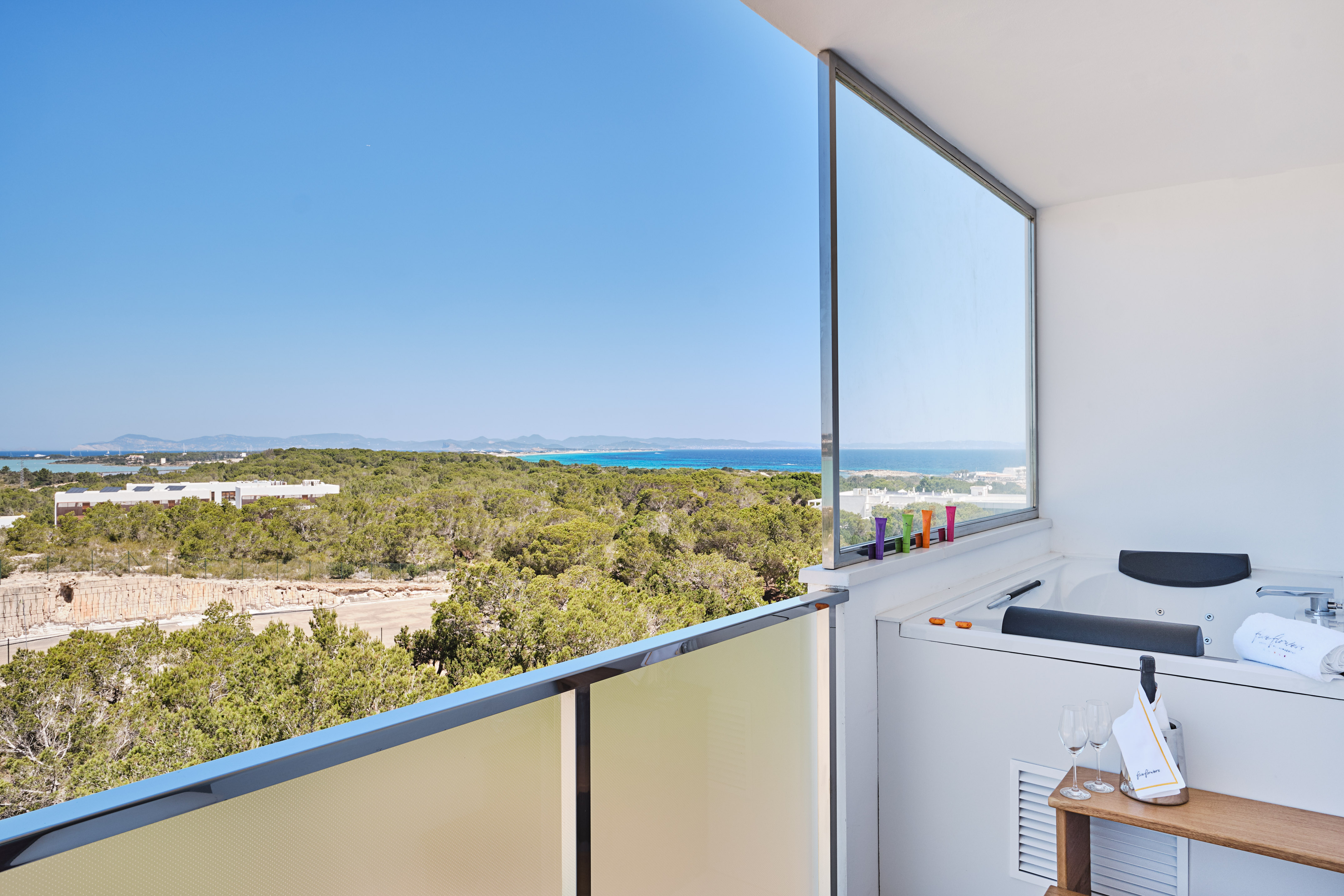 Luxury hotel balcony with hot tub and panoramic sea view.