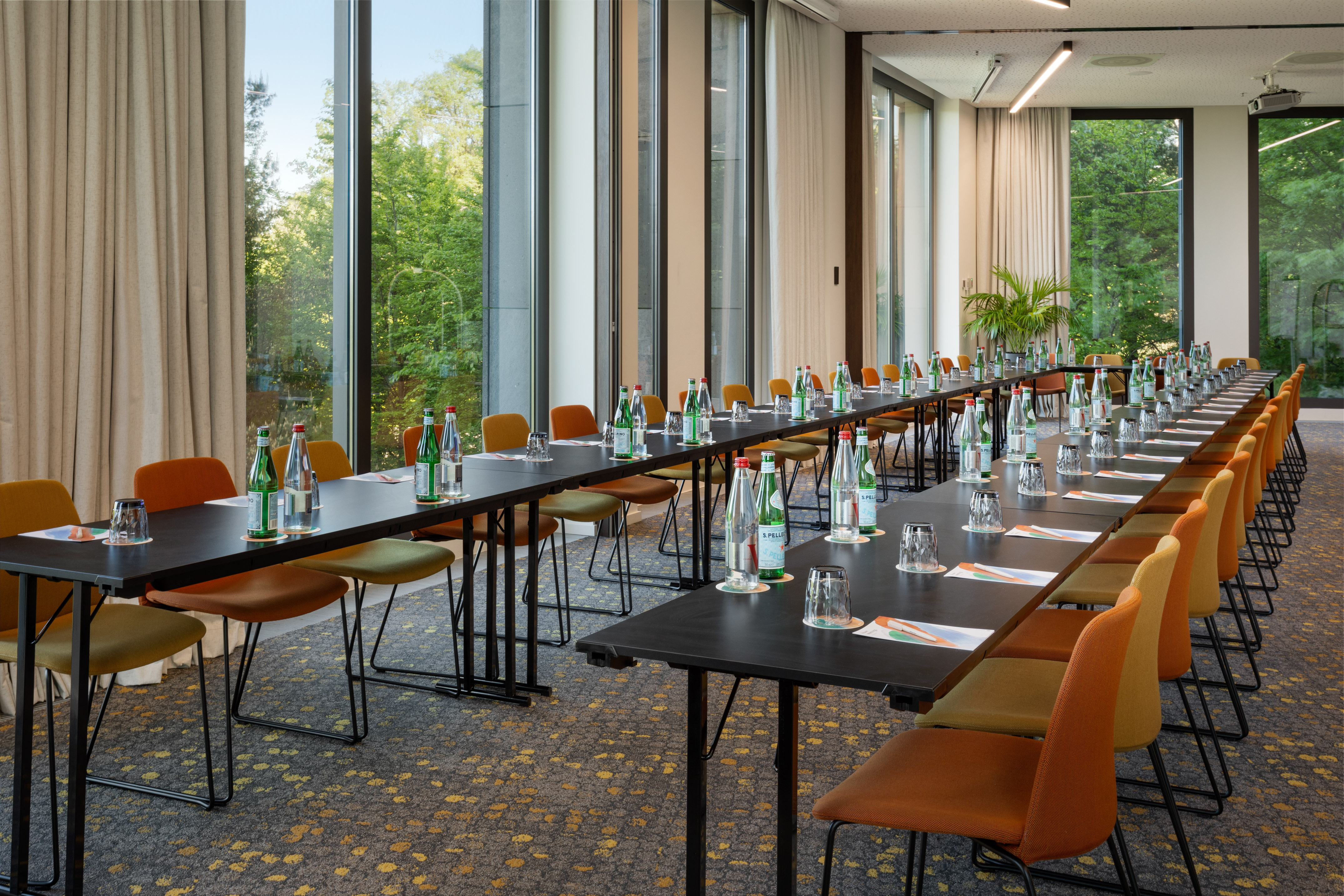 Modern conference room, U-shaped tables, colorful chairs, natural light.