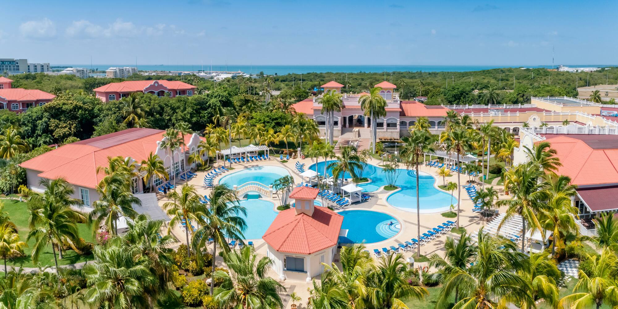 a resort with palm trees and a pool with Cayo Coco in the background