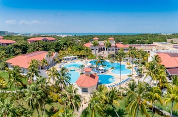 a resort with palm trees and a pool with Cayo Coco in the background