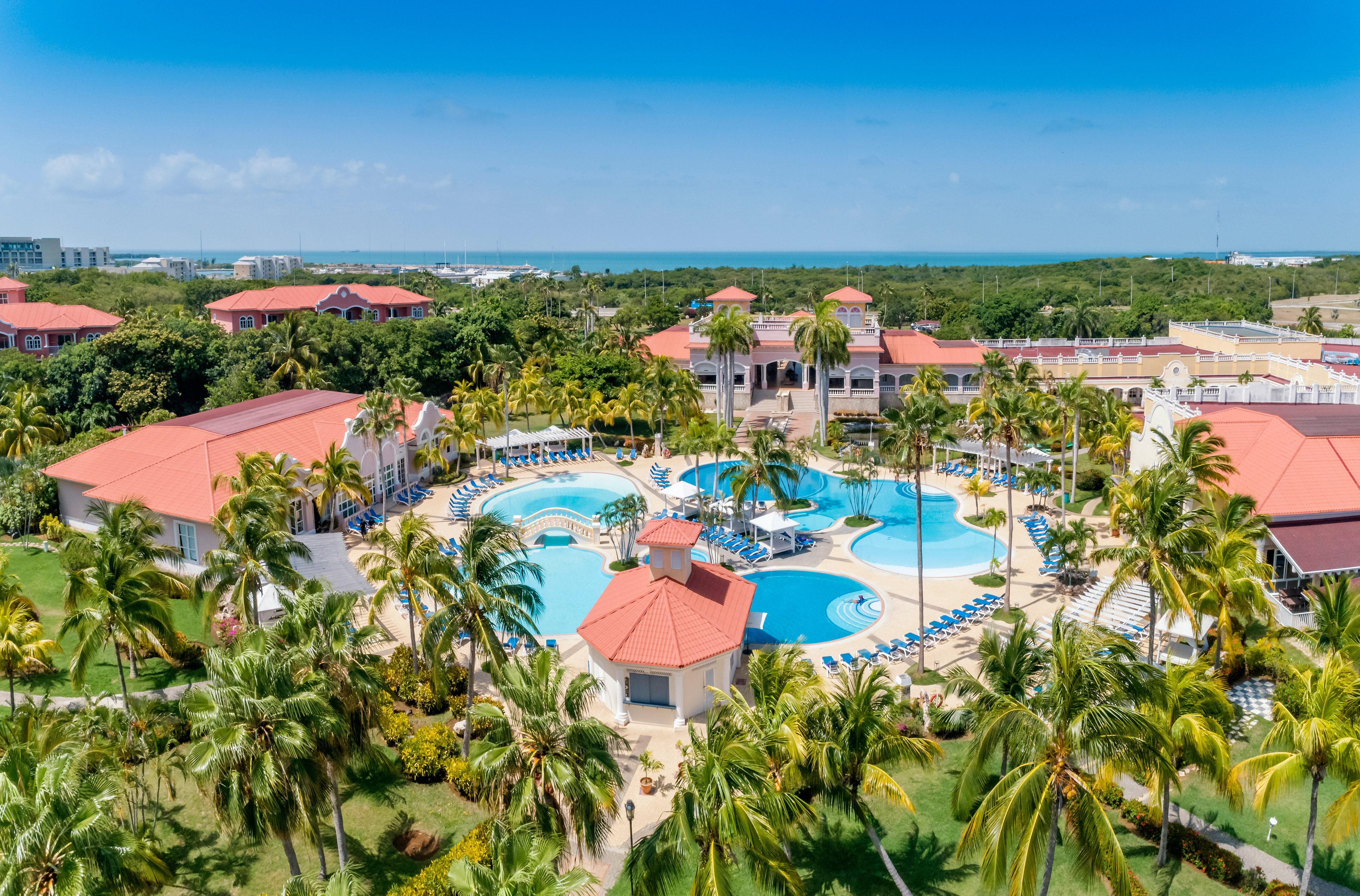 a resort with palm trees and a pool with Cayo Coco in the background