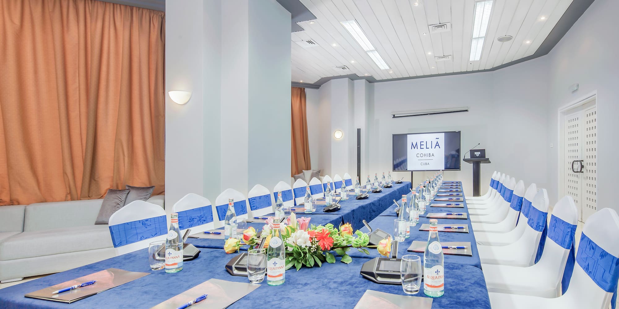 a long table with blue tablecloths and flowers on it