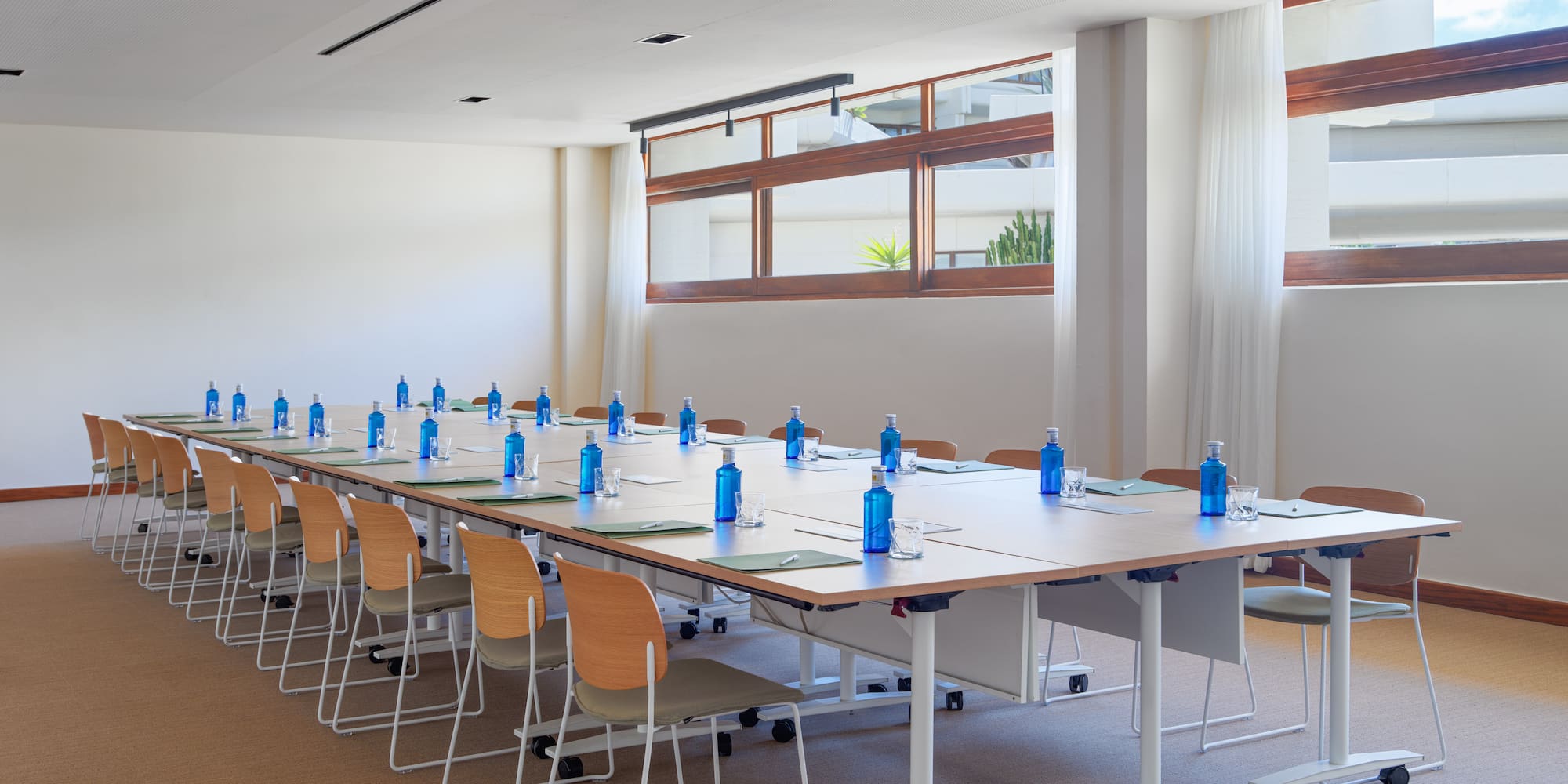 a long conference table with blue bottles and chairs