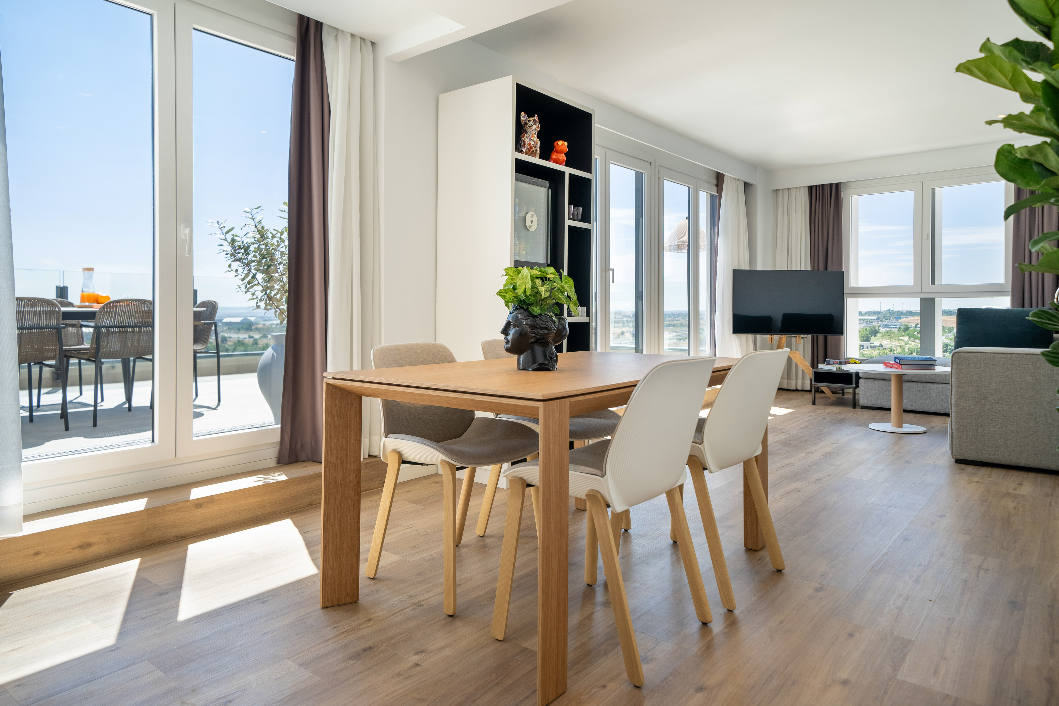Bright modern living room, dining area, and balcony with wood table and floor.