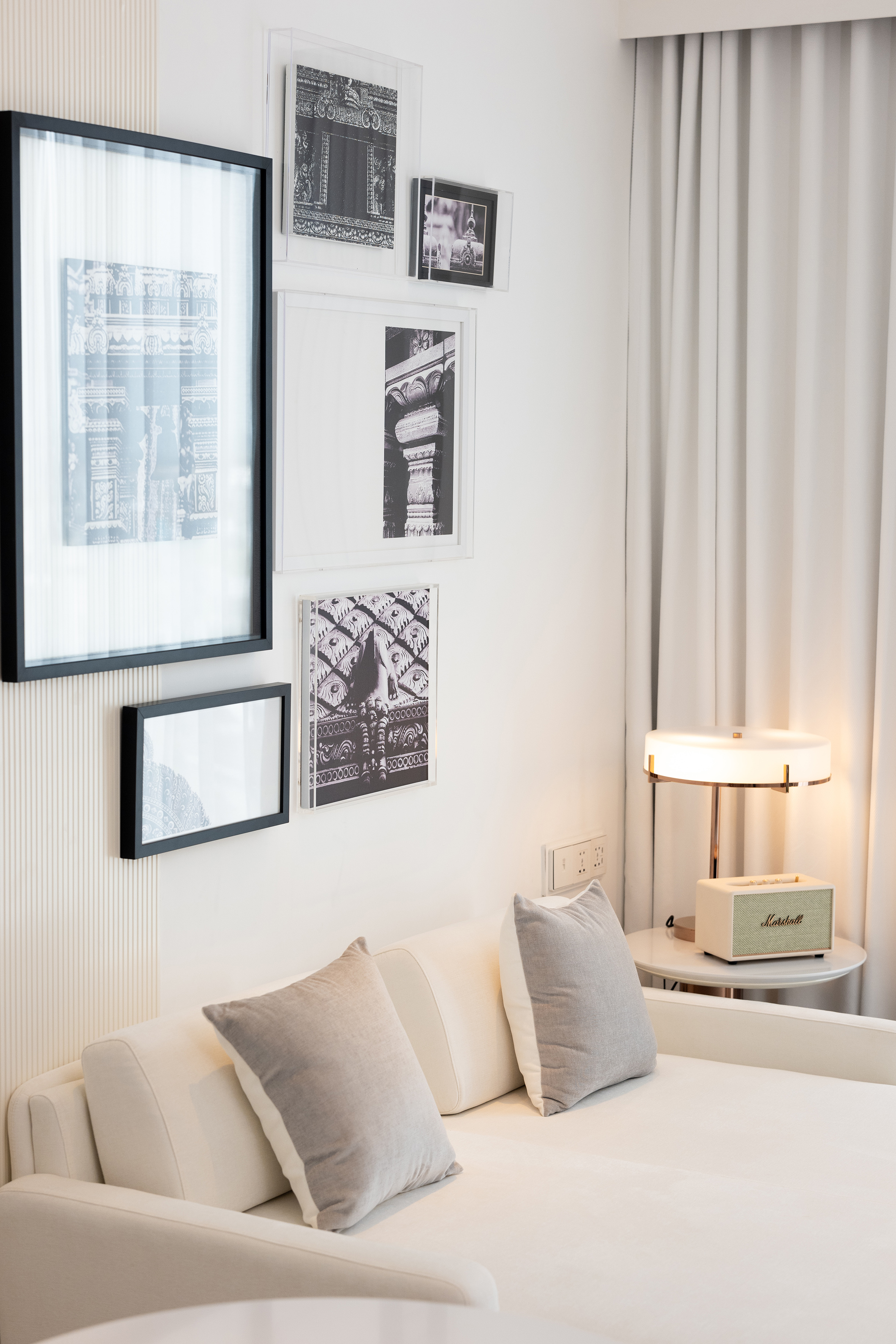 Modern interior with white sofa, monochrome art gallery, and Marshall speaker.