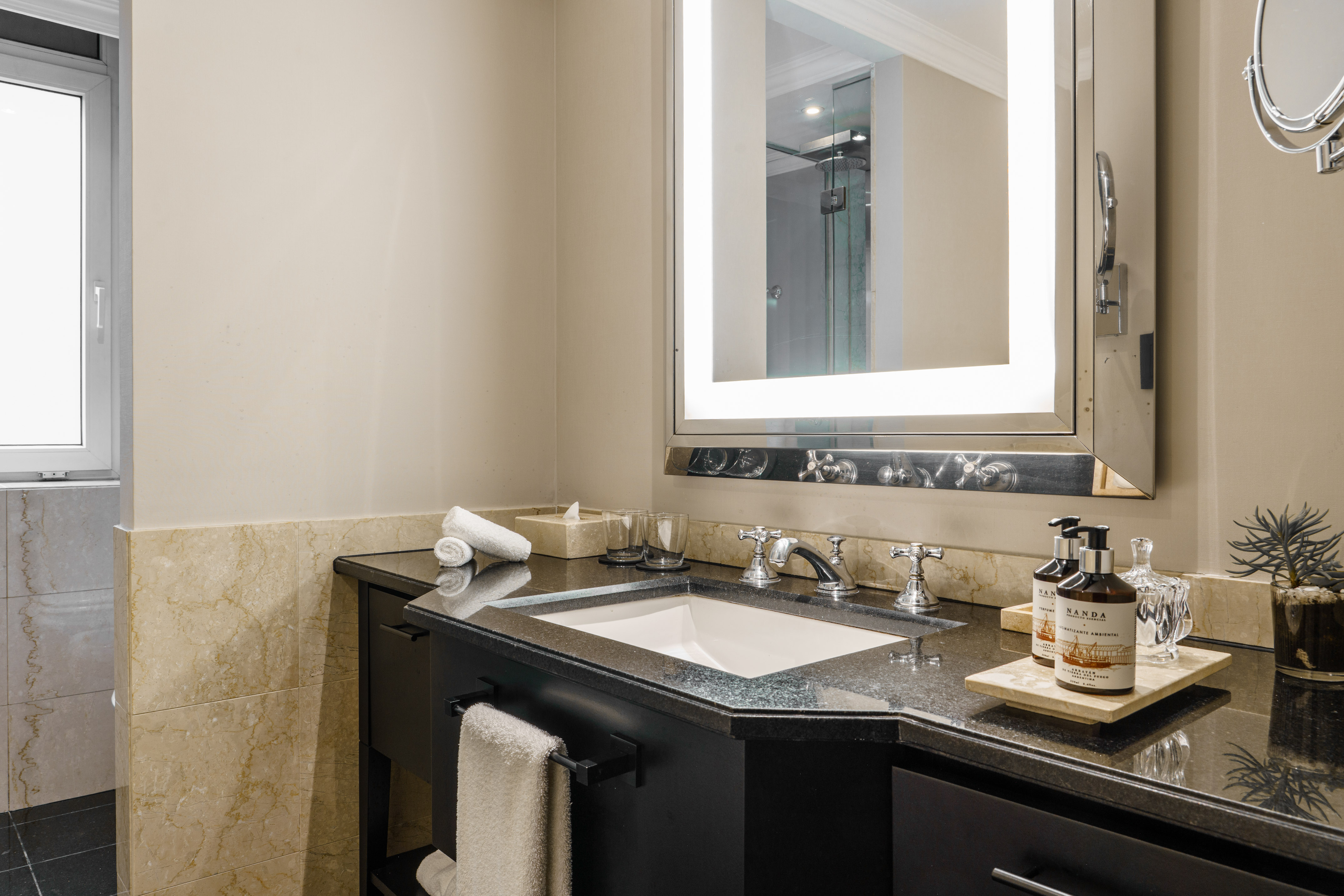Contemporary bathroom vanity with backlit mirror, sink, and dark granite countertop.