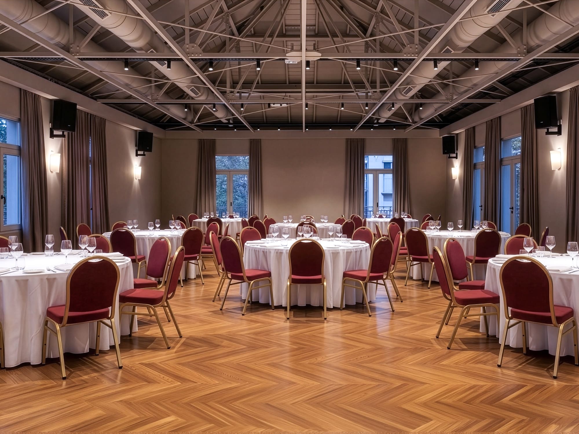 Elegant ballroom with white round tables, red chairs, and wooden parquet floor.