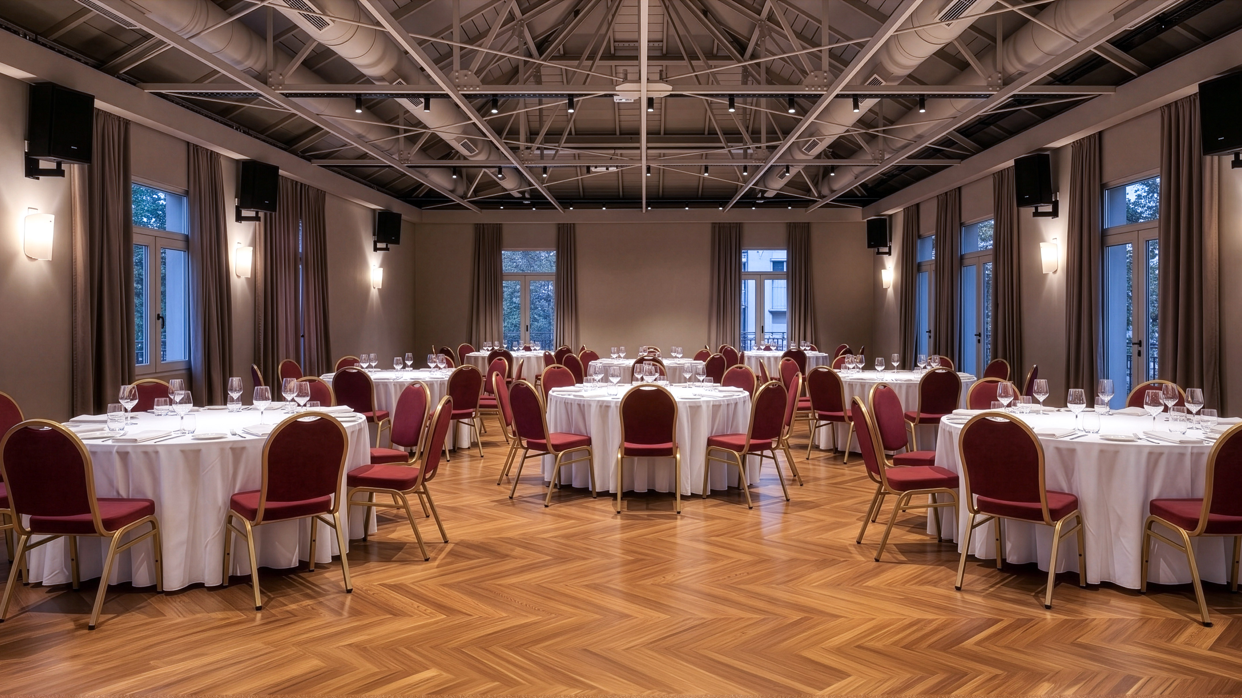 Elegant ballroom with white round tables, red chairs, and wooden parquet floor.