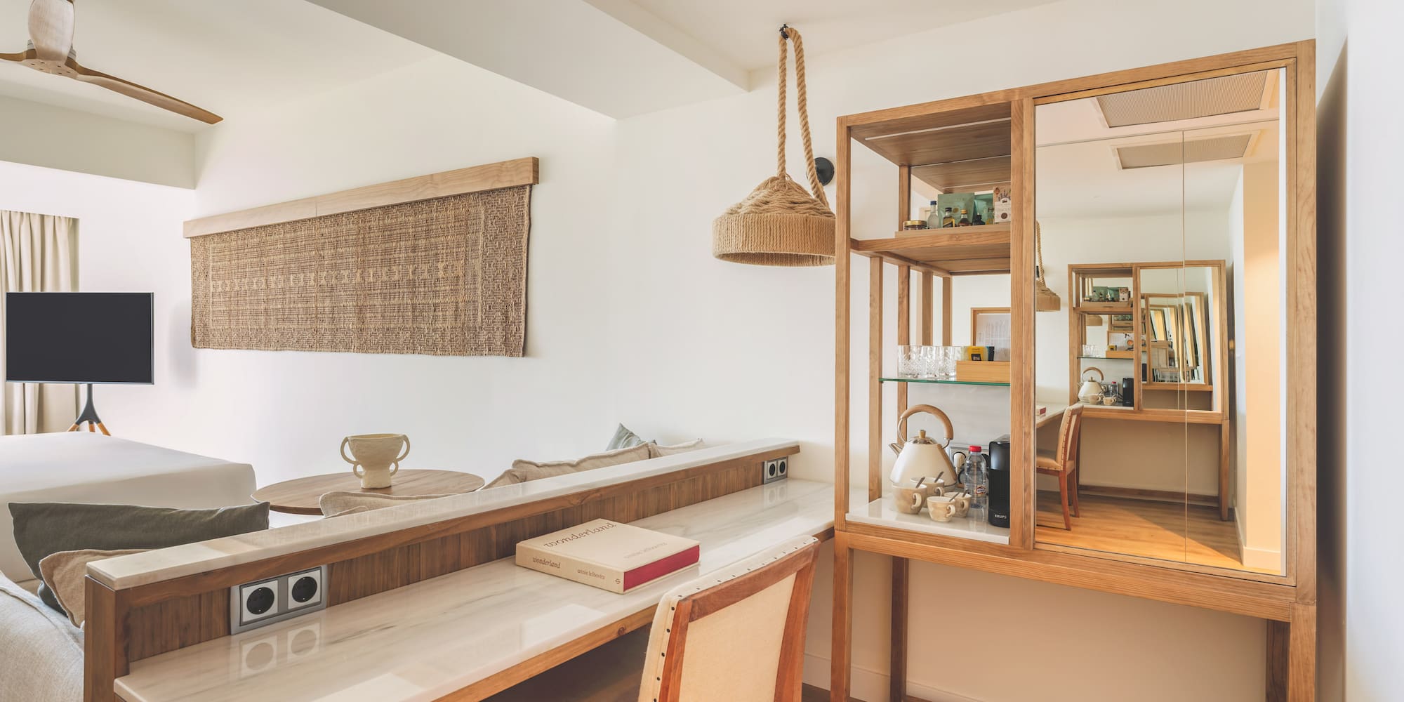 Modern hotel room with wooden desk, marble top, and natural decor.