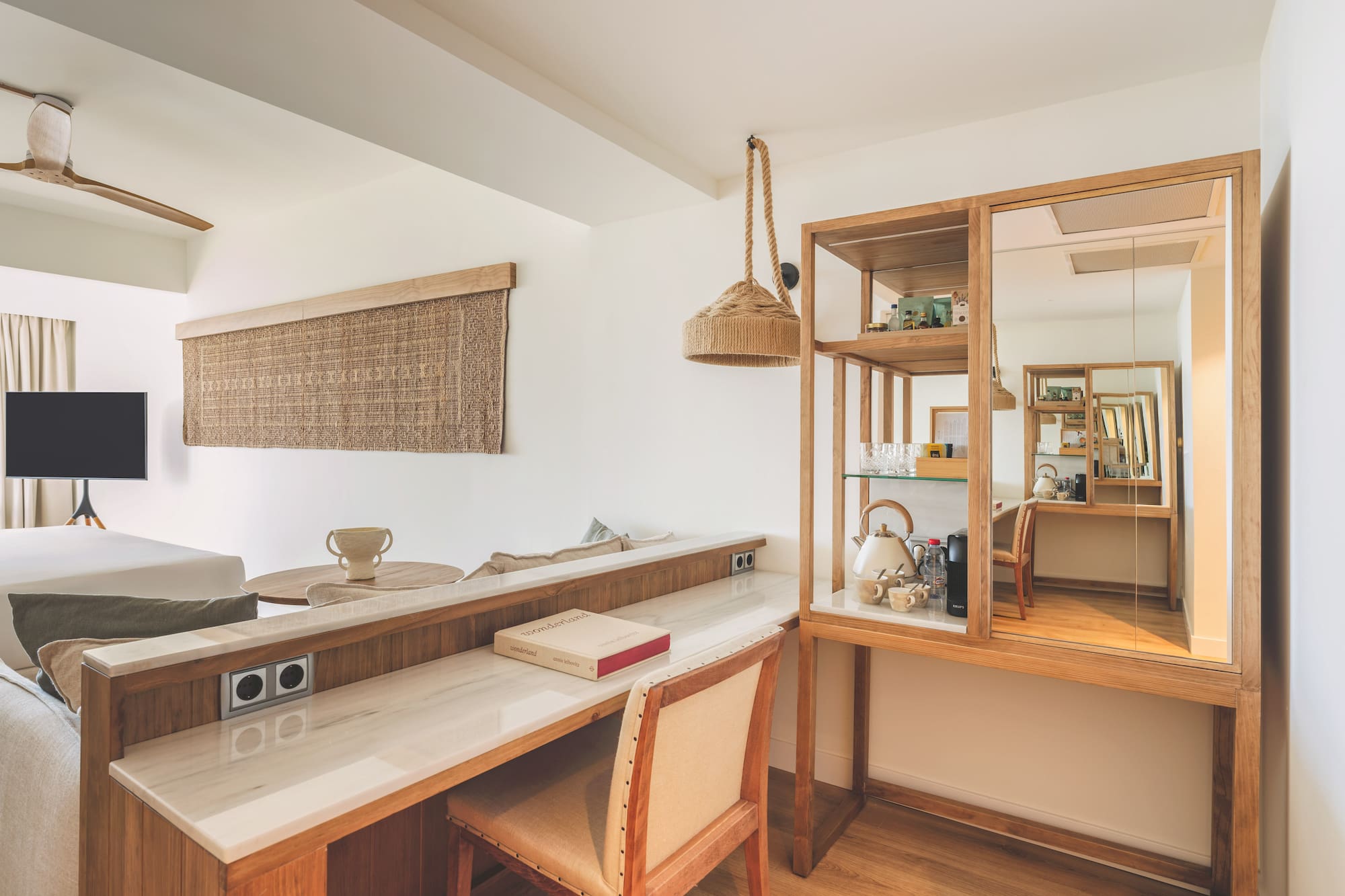 Modern hotel room with wooden desk, marble top, and natural decor.