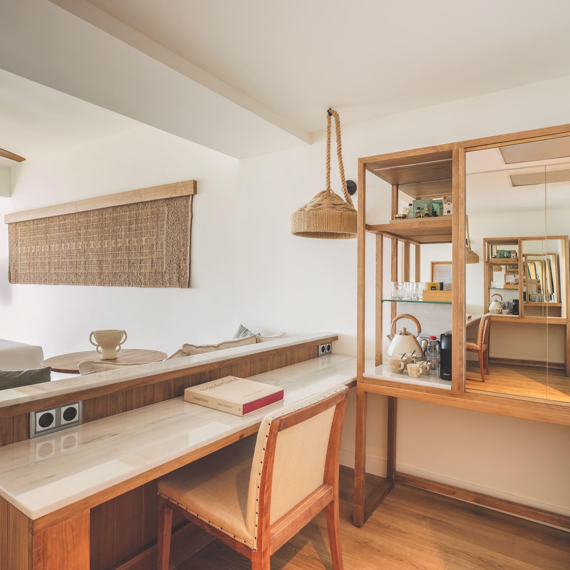 Modern hotel room with wooden desk, marble top, and natural decor.
