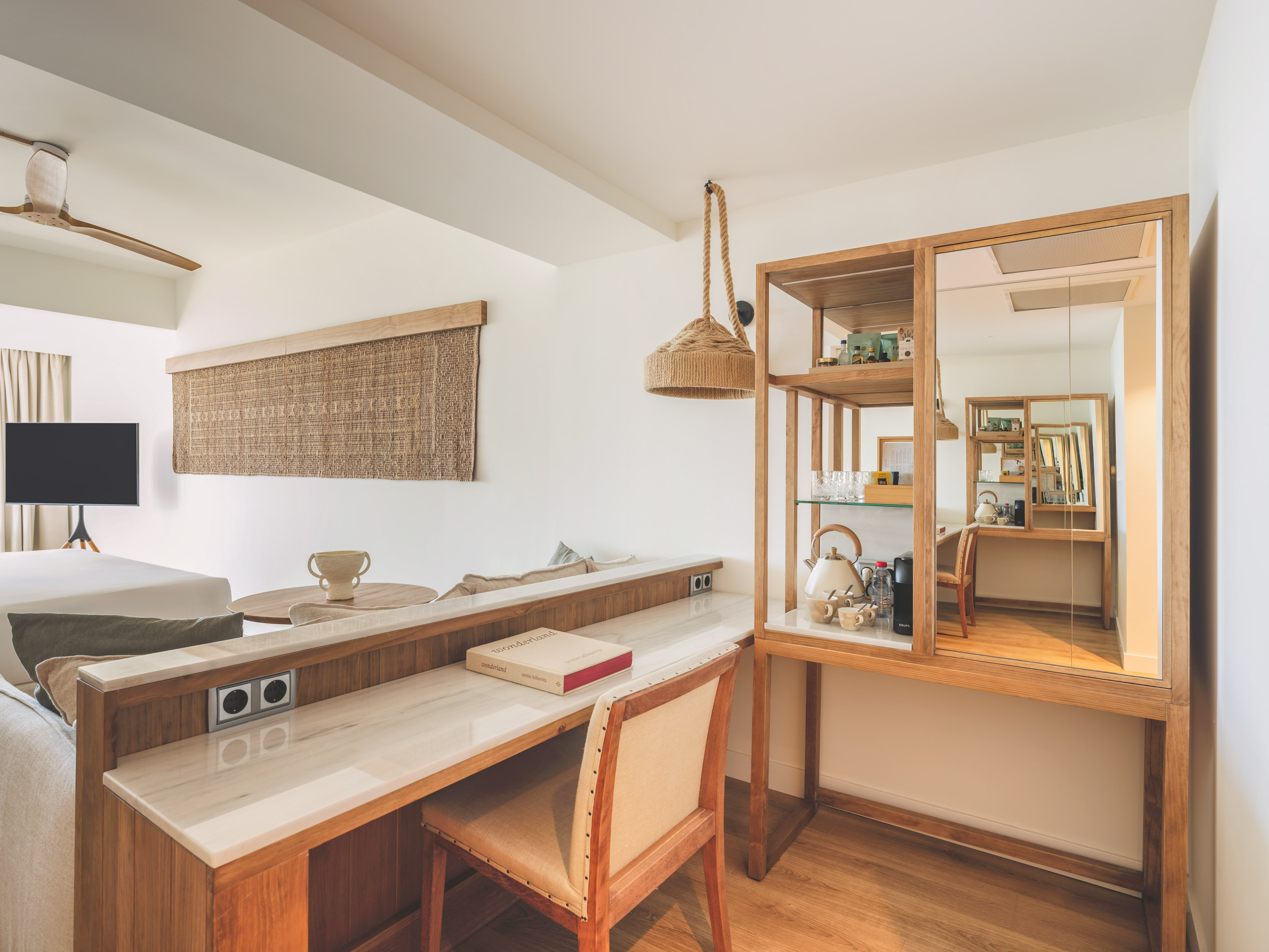 Modern hotel room with wooden desk, marble top, and natural decor.