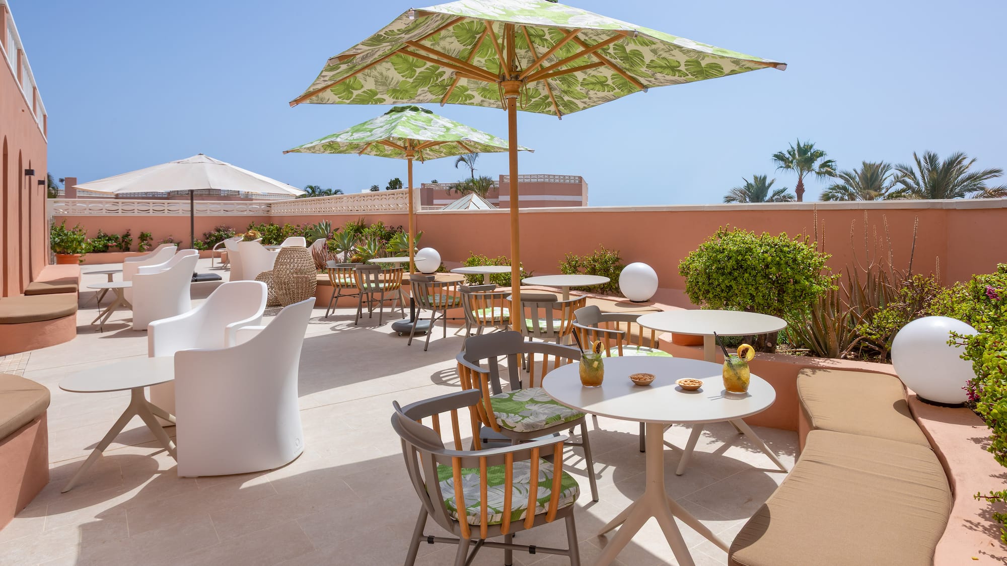 Sunny resort patio with tropical umbrellas, modern tables, and outdoor seating.