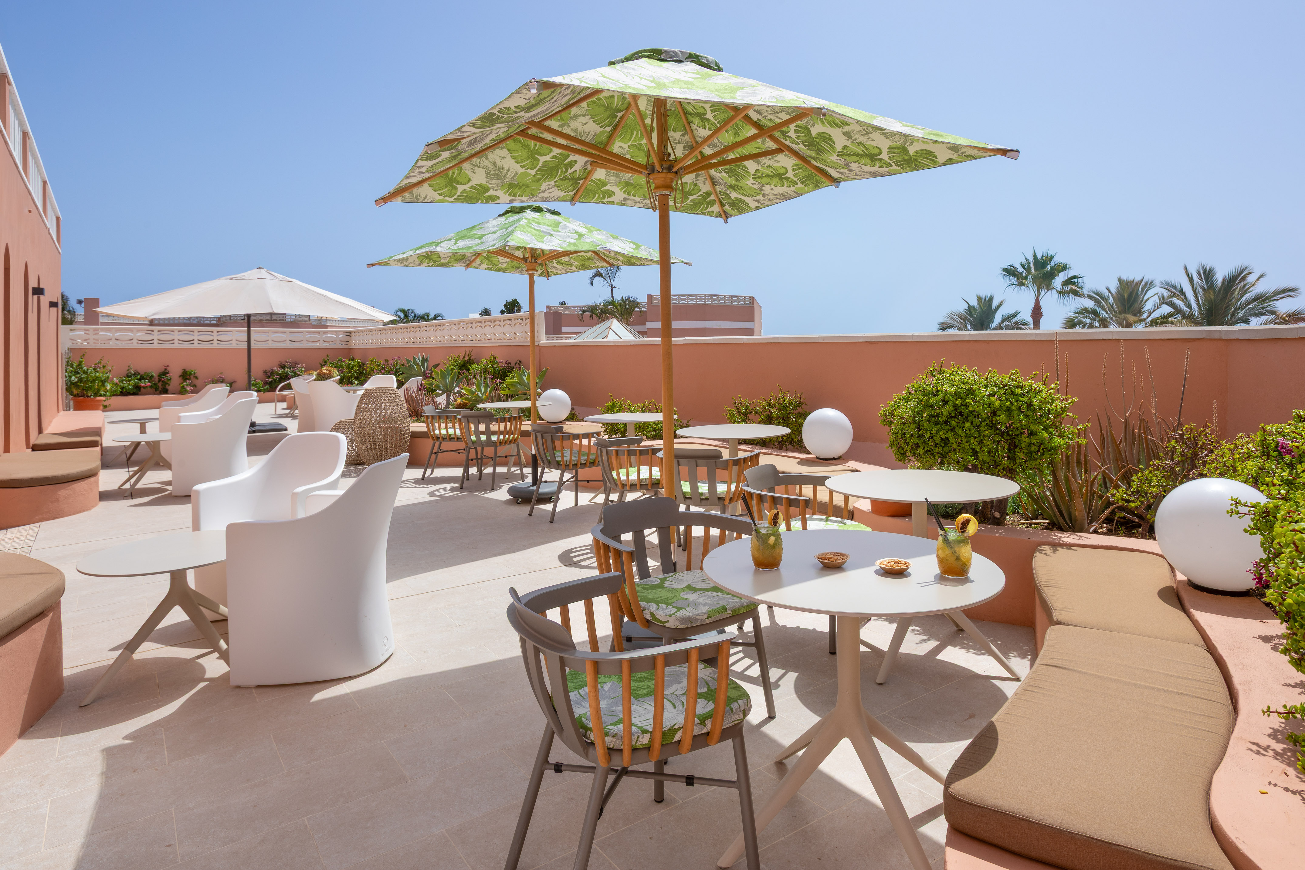 Sunny outdoor hotel patio with tropical umbrellas and modern seating.