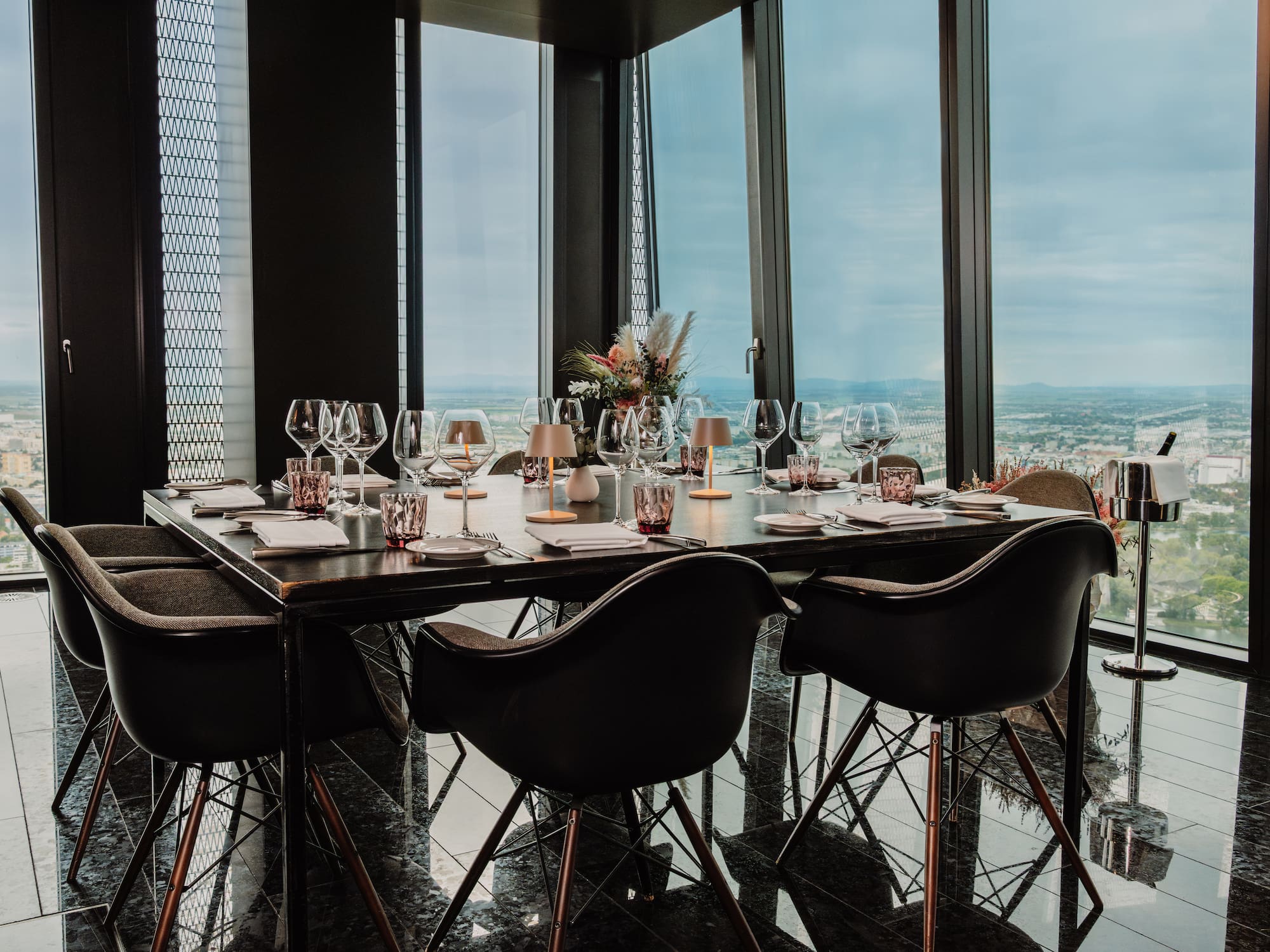 a table with wine glasses and a vase of flowers in front of a window